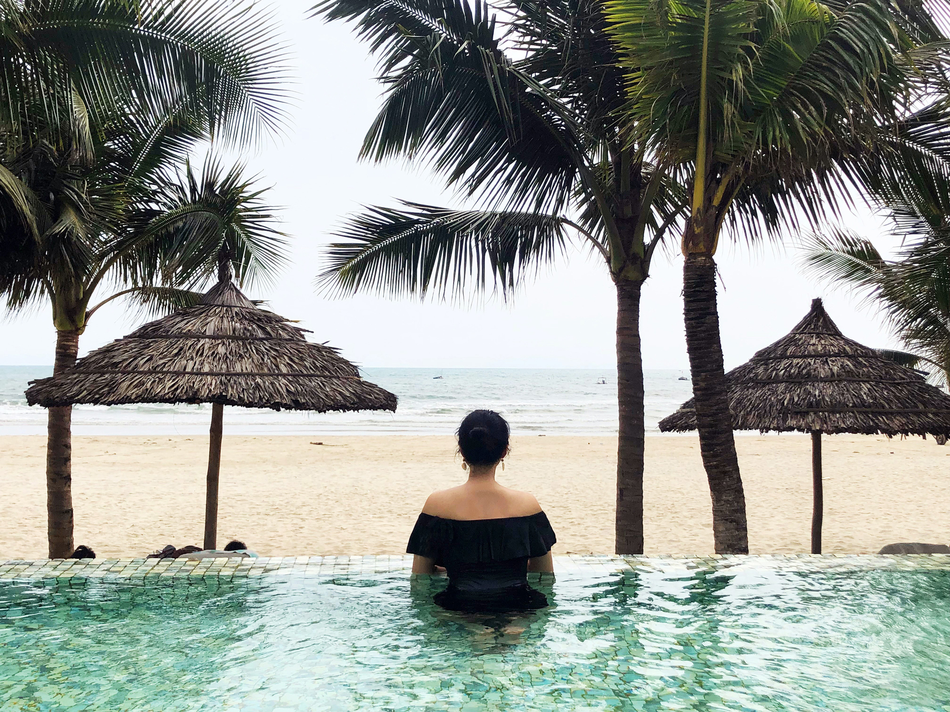 A woman looking out to sea while in a resort pool