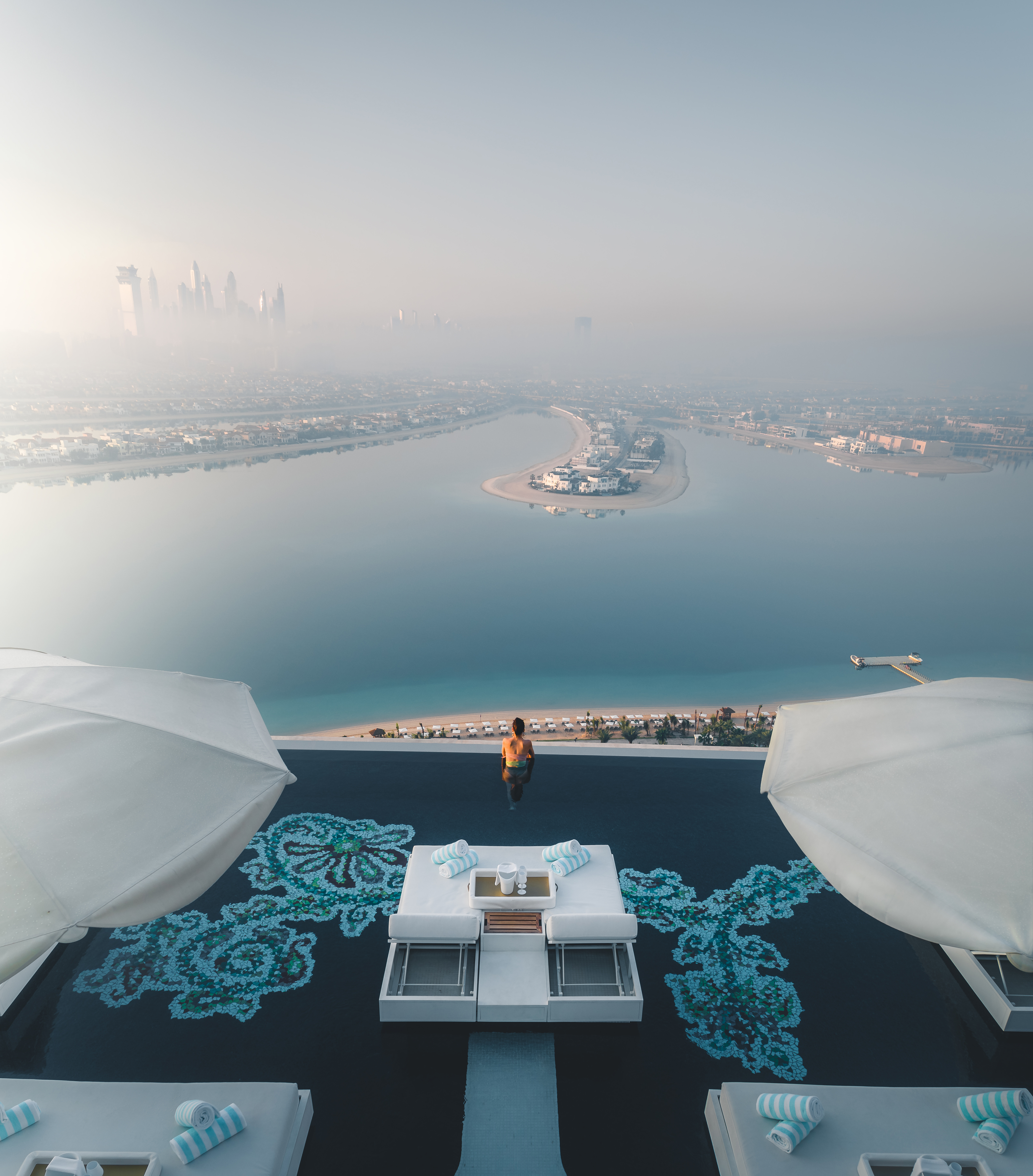 A woman looking at a skyline from a rooftop pool
