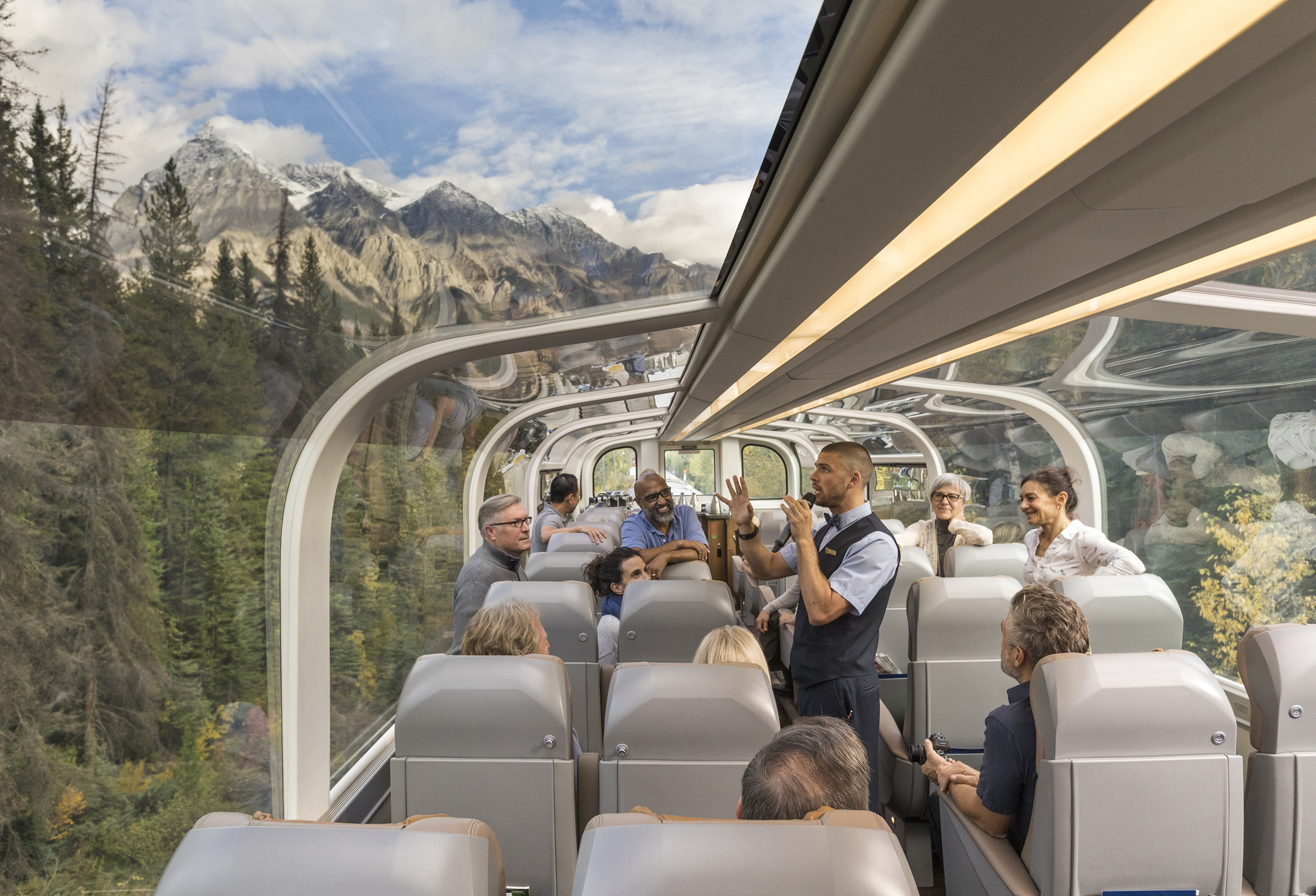 Passengers aboard The Rocky Mountaineer glass carriage listening to a host talk about the landscape