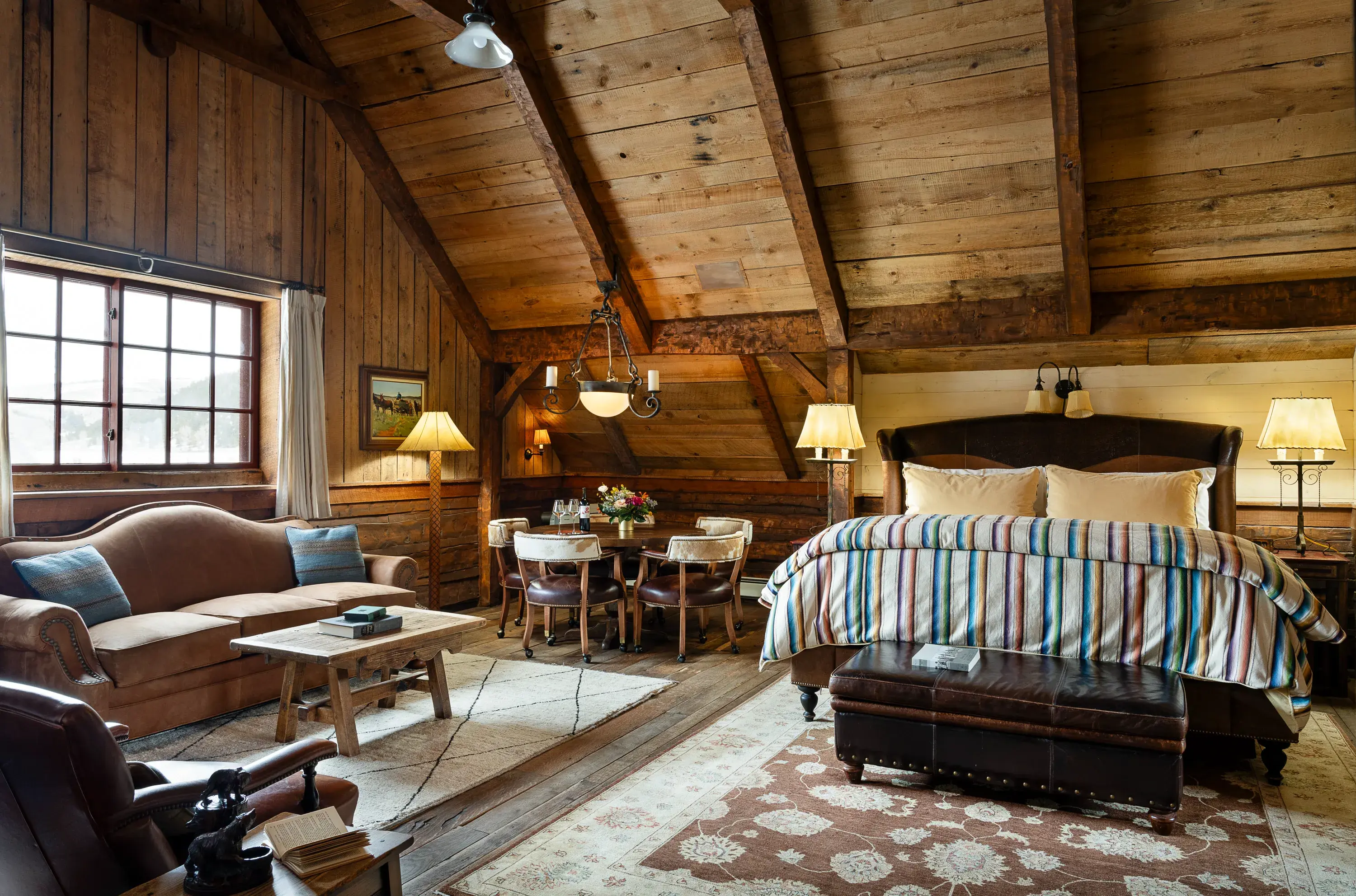 Loft room in the Barn at The Ranch at Rock Creek in Montana featuring a large bed and ranch-style furniture beneath vaulted ceilings