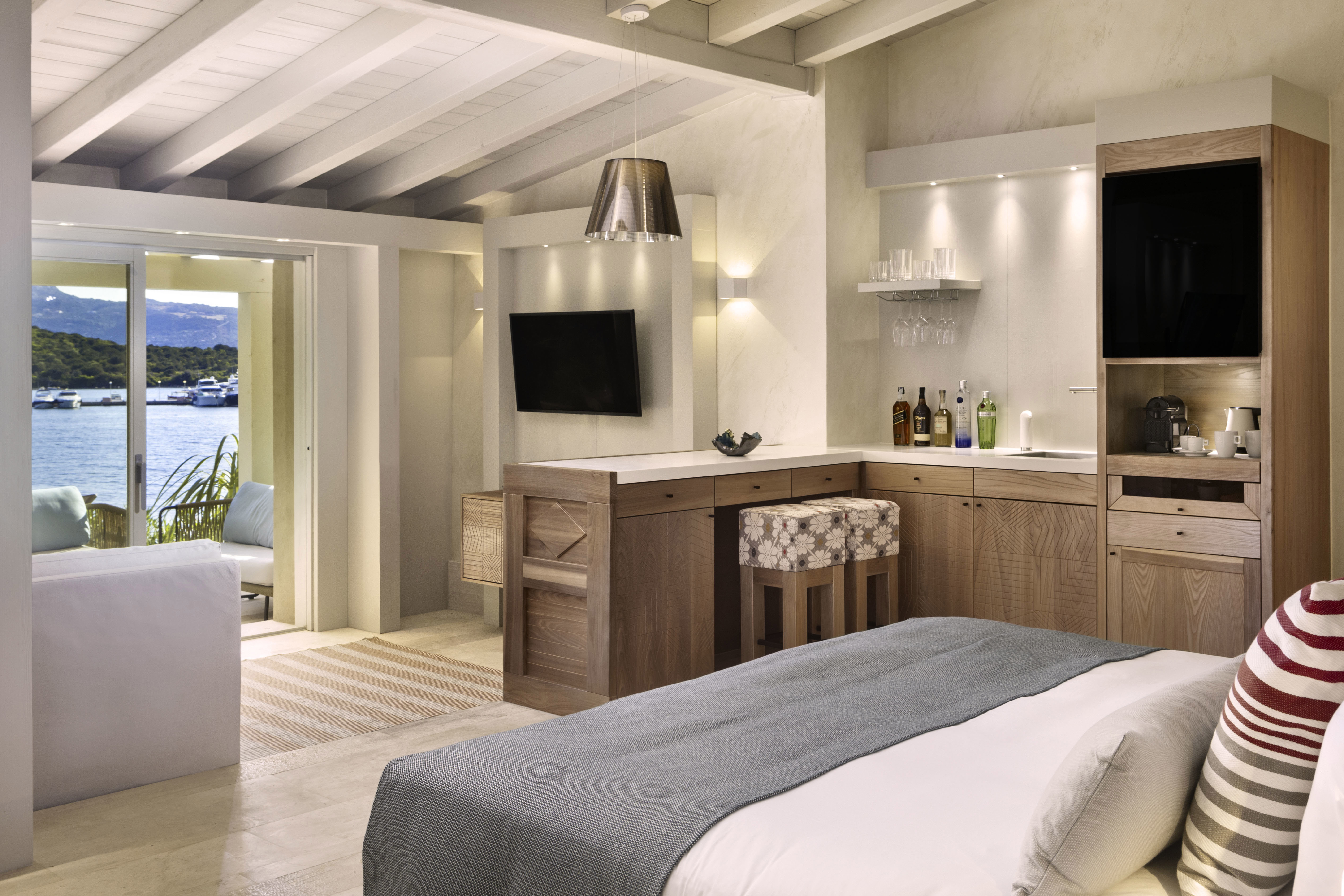 The sleek interior of a suite featuring a bed, coffee area and seating with a sliding door and a view of the sea
