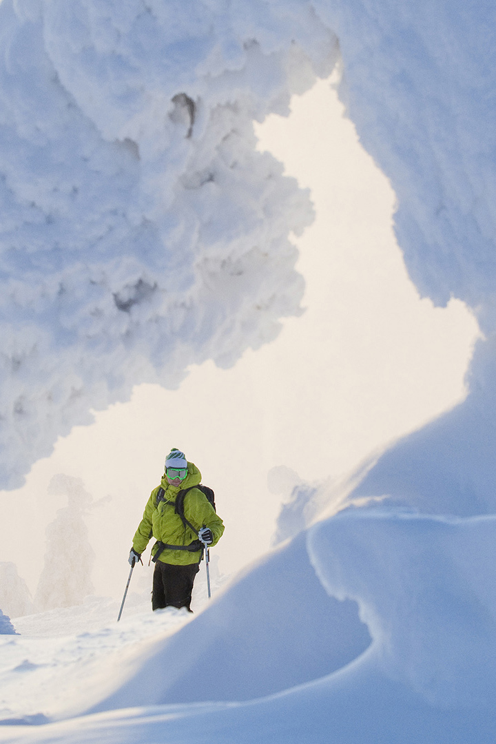 Skier in green jacket looking through a snow cave