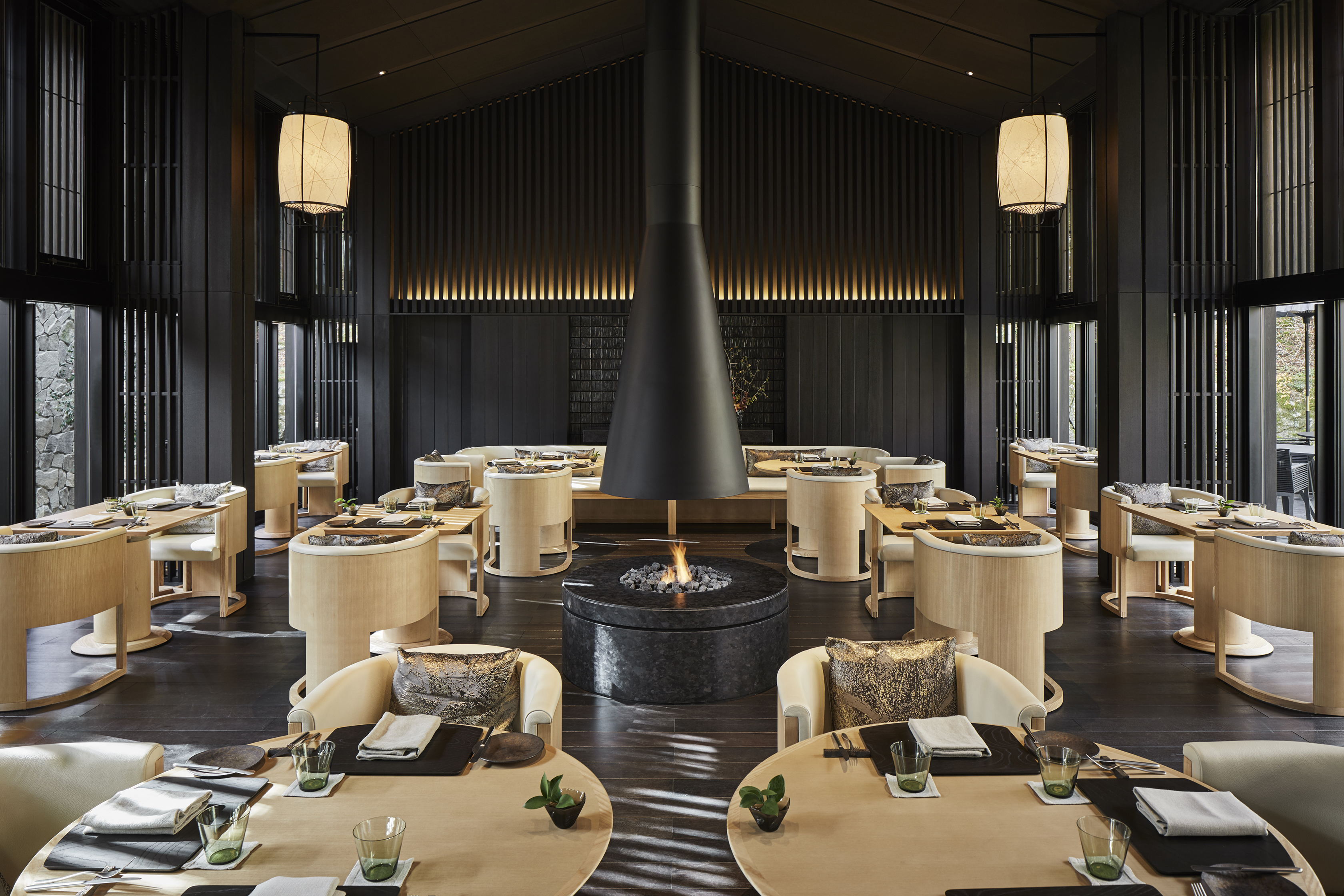 The Living Pavilion Restaurant featuring pale wood dining furniture surrounding a fireplace made from dark stone