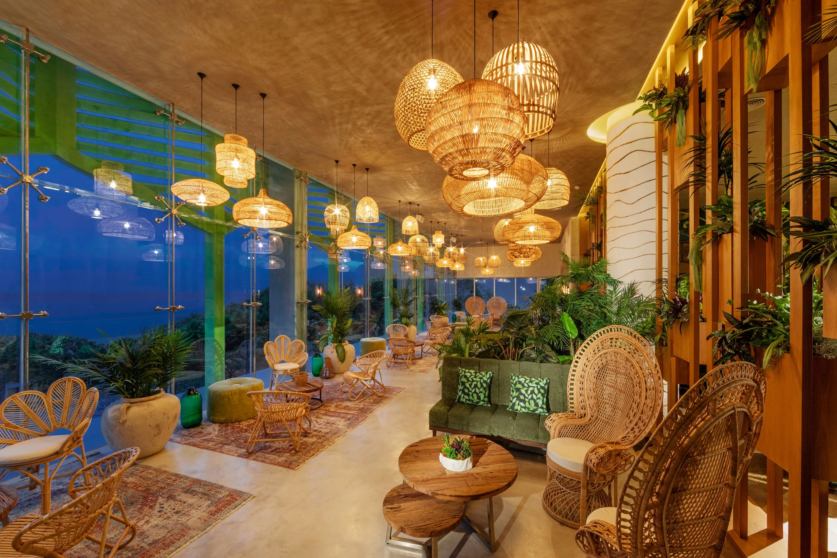Stylish lounge with woven pendant lights, rattan seating and ocean views through glass walls.