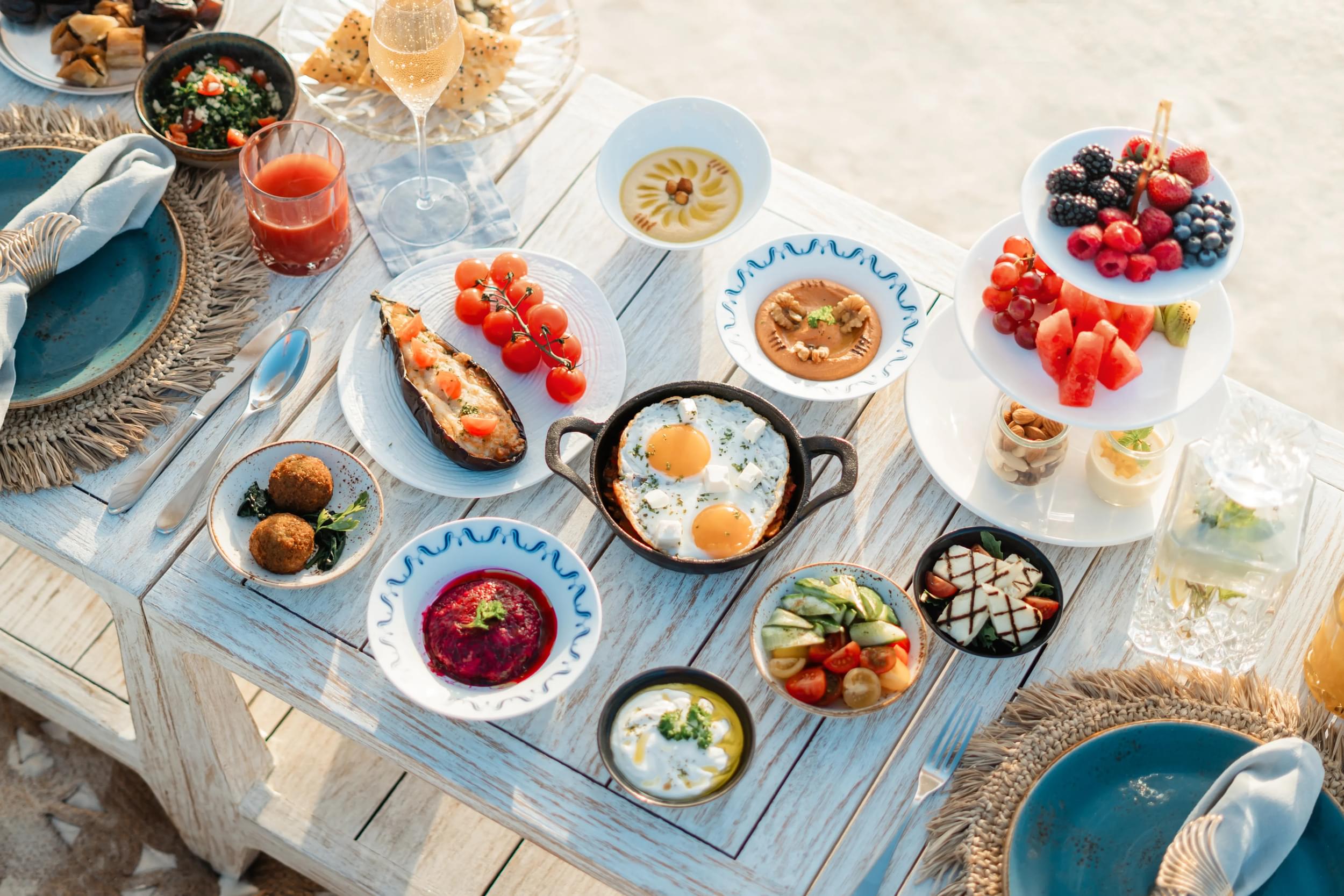 A dinging spread on a pale wooden table featuring eggs, fruits and dips at The Nautilus, Maldives