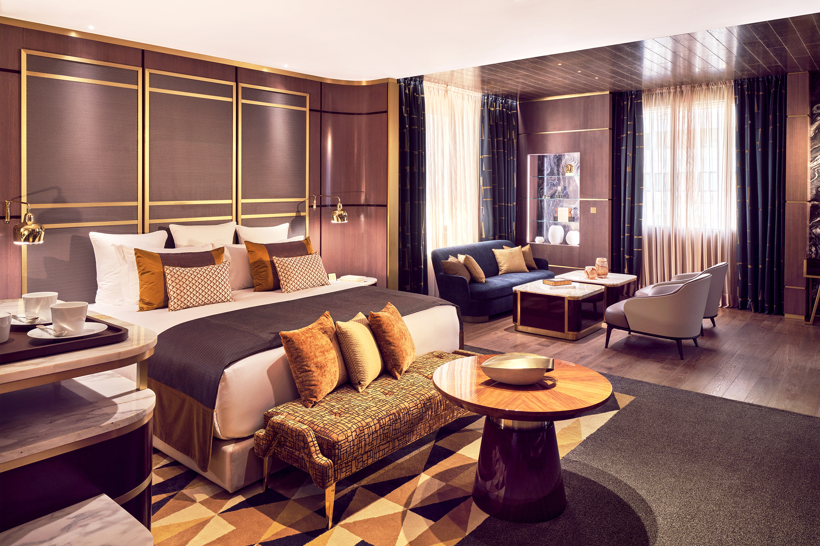 A Junior Deluxe Suite at Royal Mansour Casablanca featuring a plush bed and seating area, gold furnishings and deep purple walls