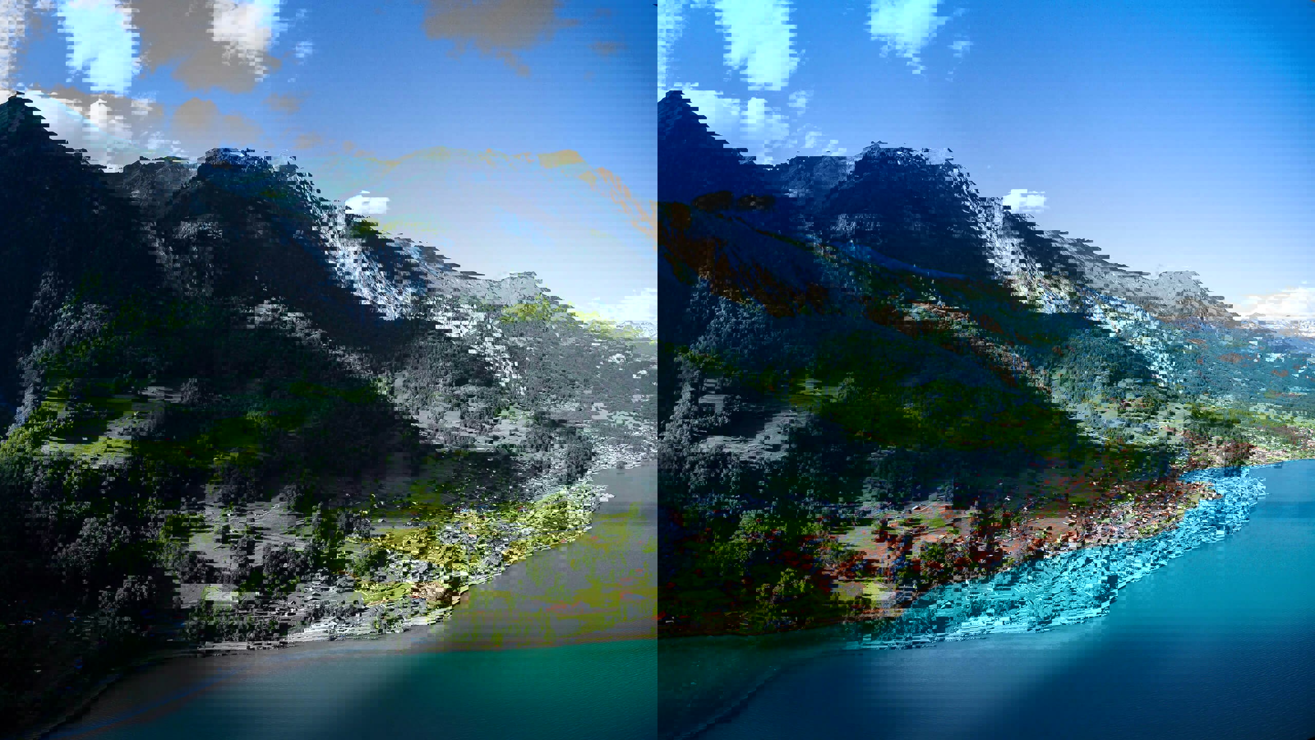 A large mountain by the side of Lake Brienz with a town at its base by the water