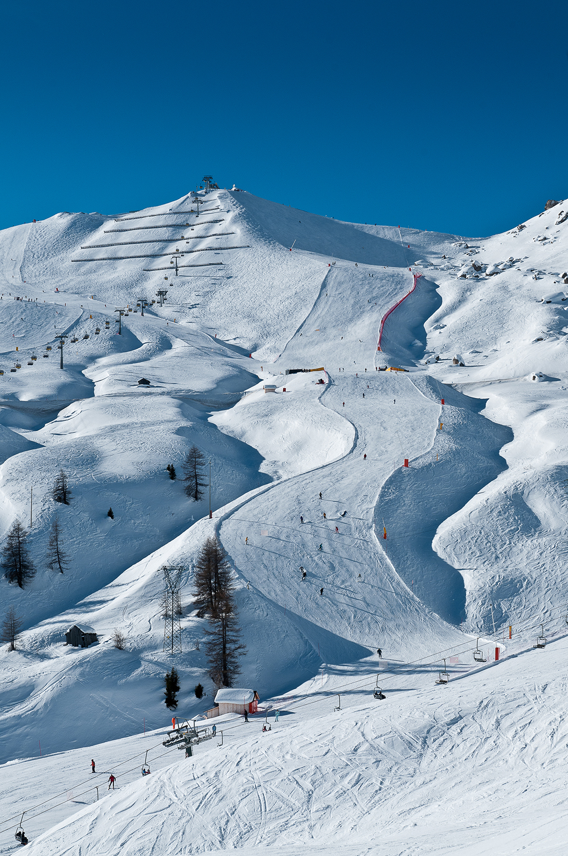 People skiing downhill on a run in the Dolomites, Italy by Giuseppe Ghedina