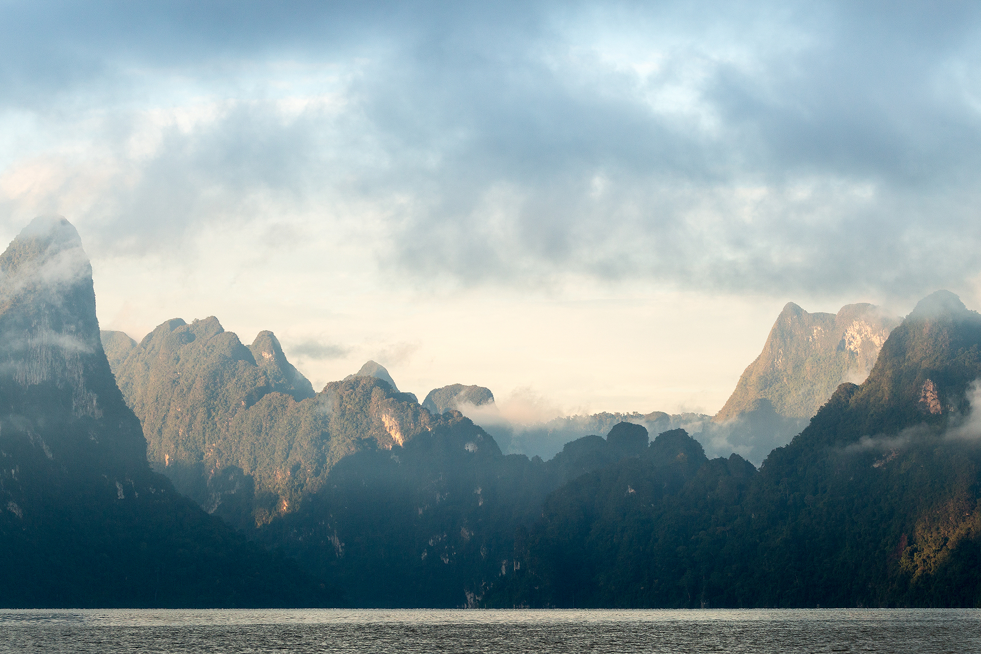 The rugged landscape and cloudy sky of Elephant Hills, Cheow Larn Lake in Khao Sok National Park Thailand