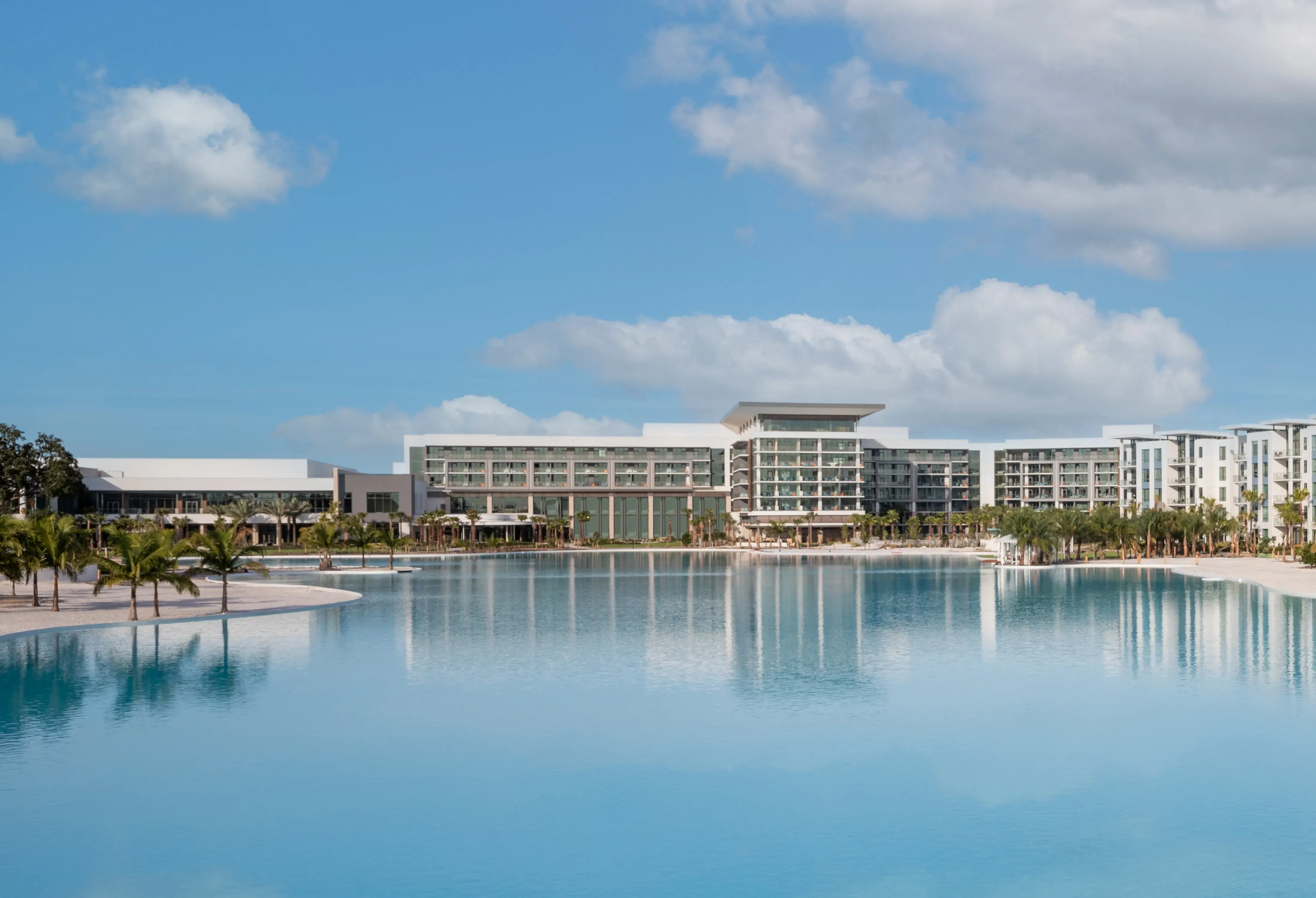 Lakeside exterior view of Conrad Orlando in Florida featuring modern architecture, palm‑lined waterfront, and a crystal‑clear lagoon.