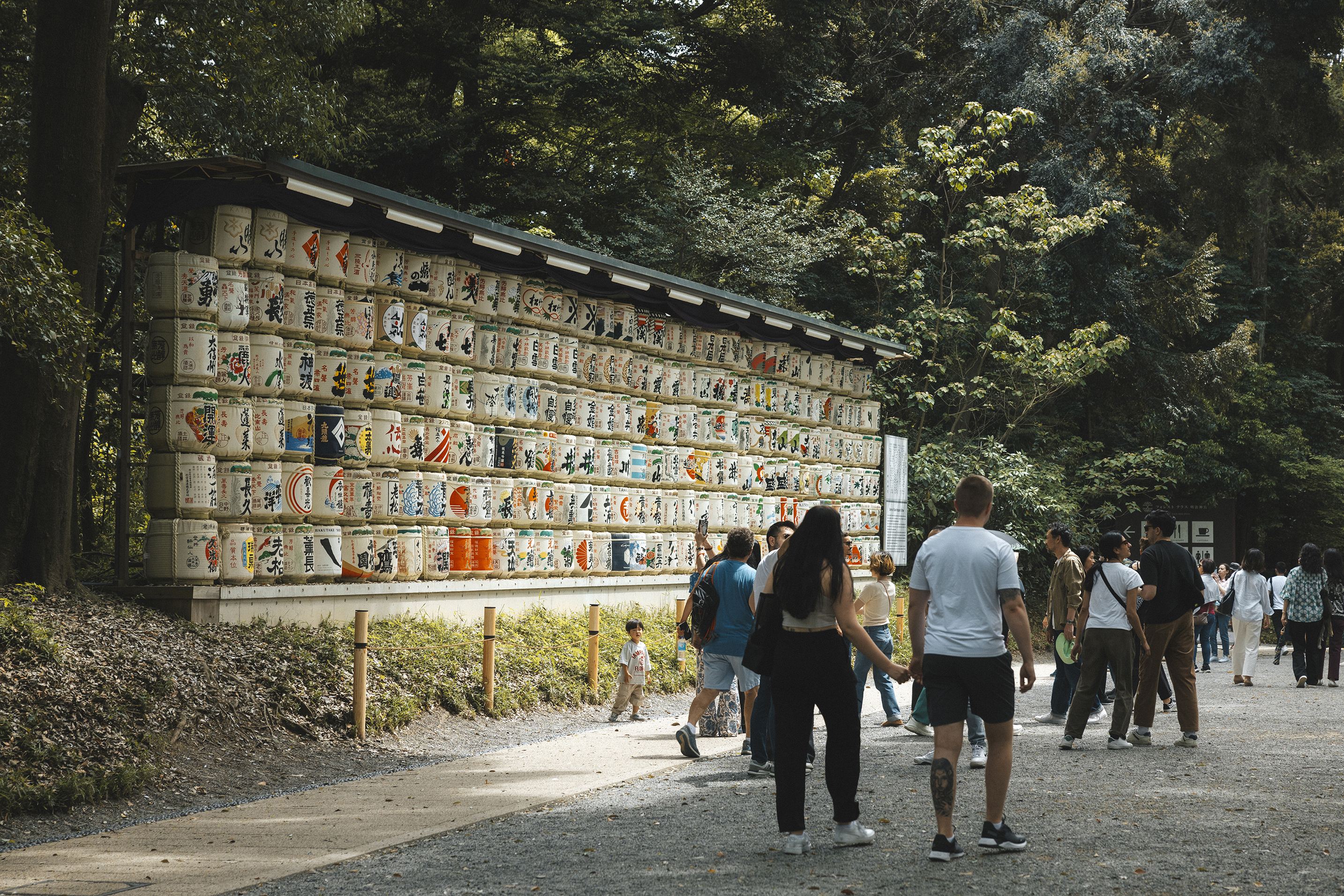 People walking past the sake barrells at the enterance of Meiji Jingu Shrine in Tokyo
