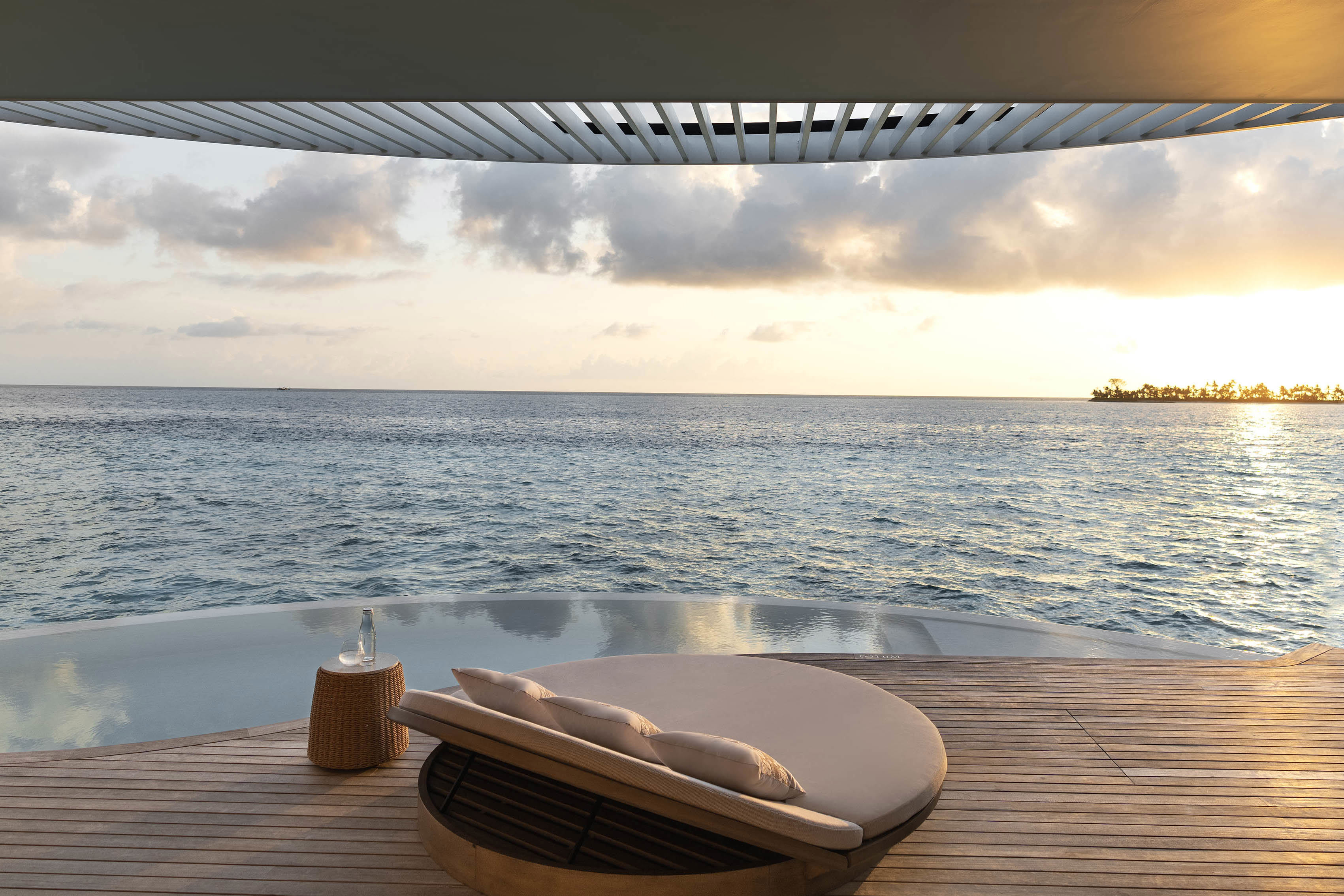 Sunset over a lagoon villa with sun lounger bed looking out to sea