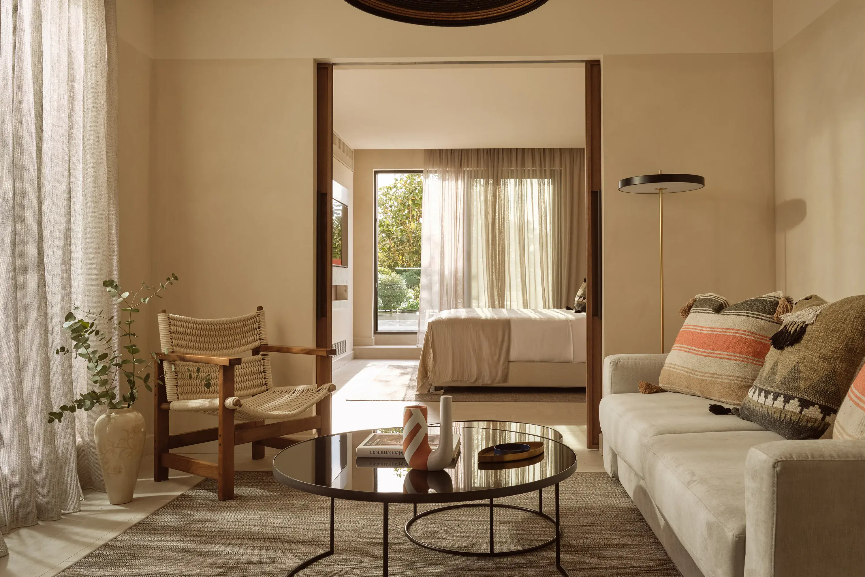 Elegant panorama suite at Eagles Palace in Greece featuring a serene living area and sunlit bedroom with natural, earthy décor.