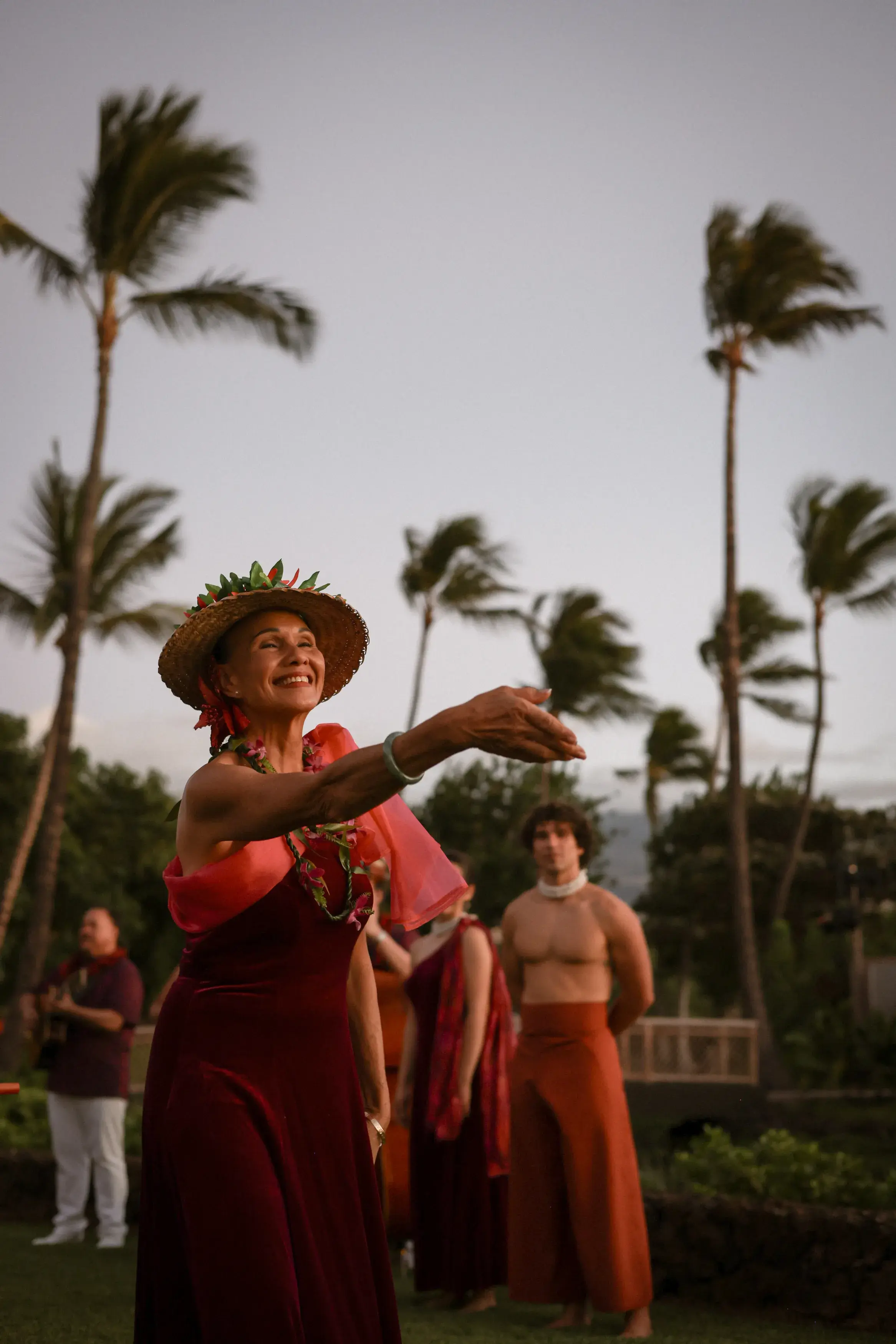 A person hula dancing in a hat in front of other performers at Rosewood Kona Village in Hawaii