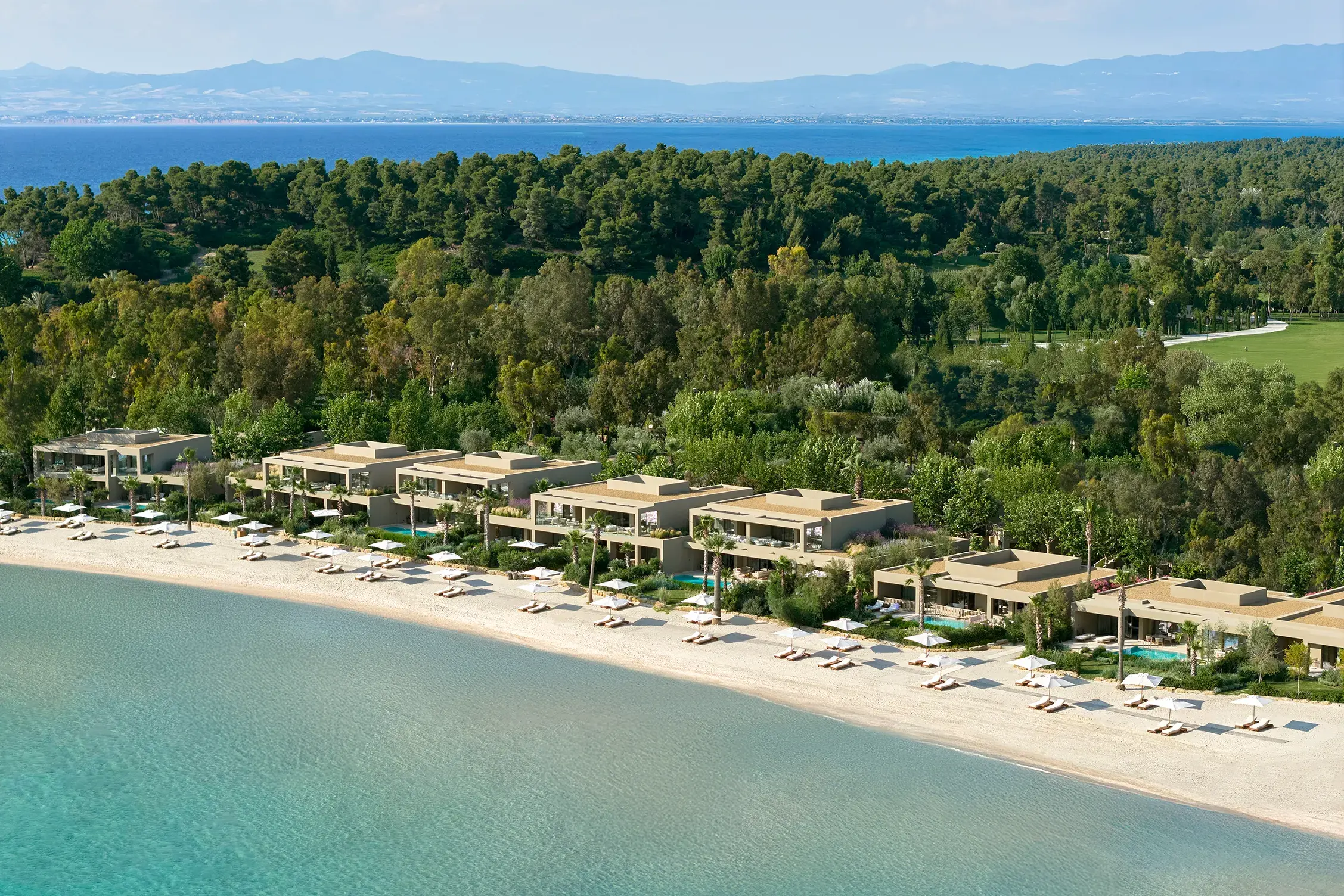 Aerial view of the beachfront residences at Sani Asterias in Halkidiki with turquoise waters, white sand and lush forest surroundings.