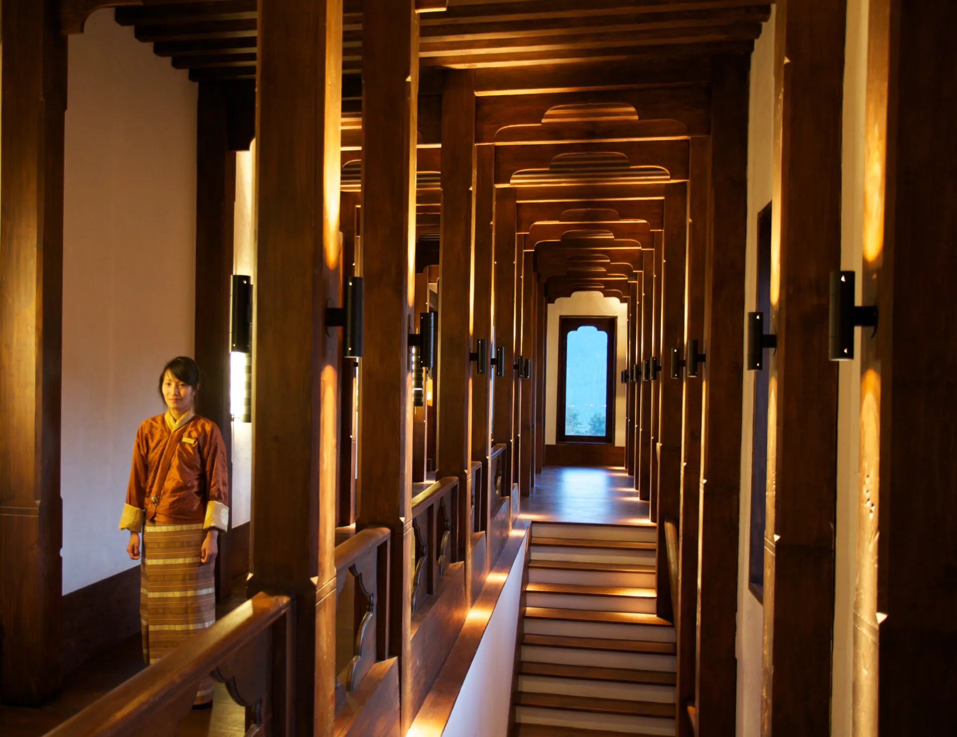 Elegant wooden corridor with warm lighting and traditional design details in a luxury lodge.