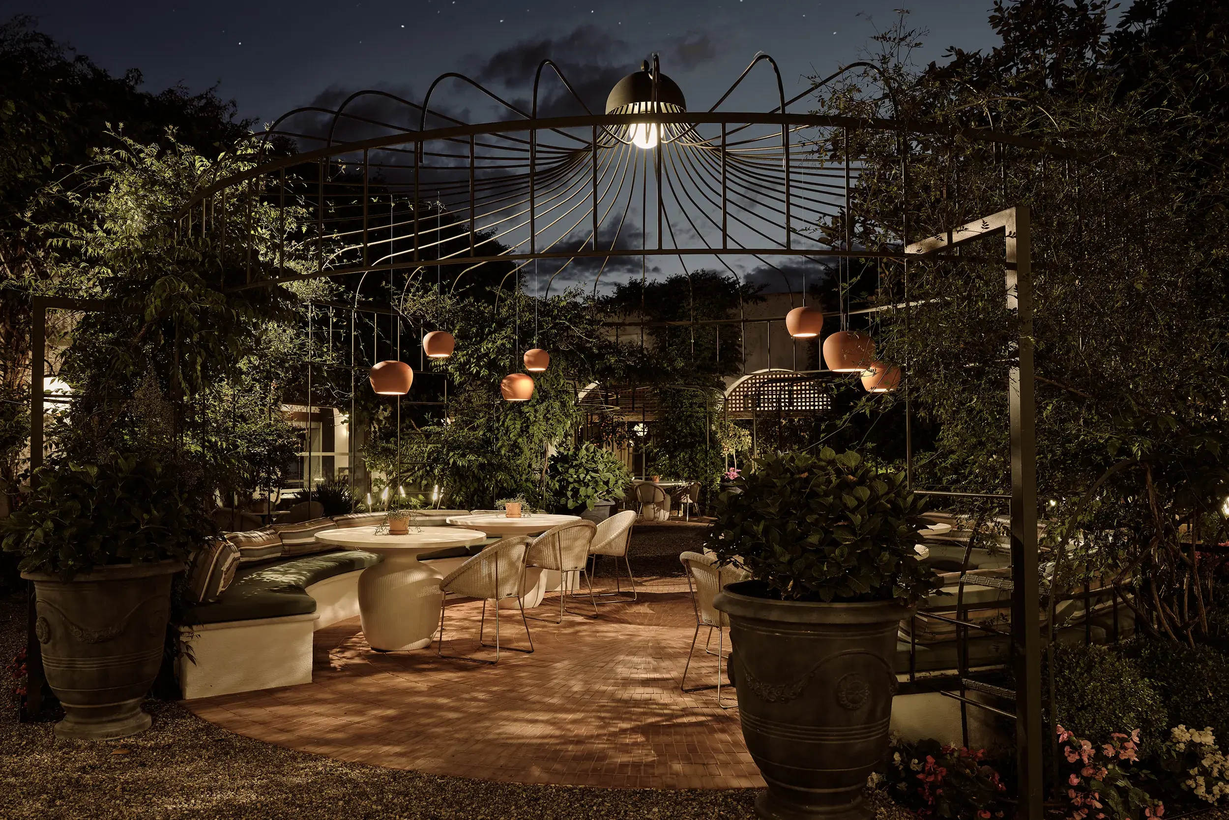 Atmospheric outdoor dining at Eagles Palace in Greece featuring softly lit garden seating under elegant pergola lighting at night.