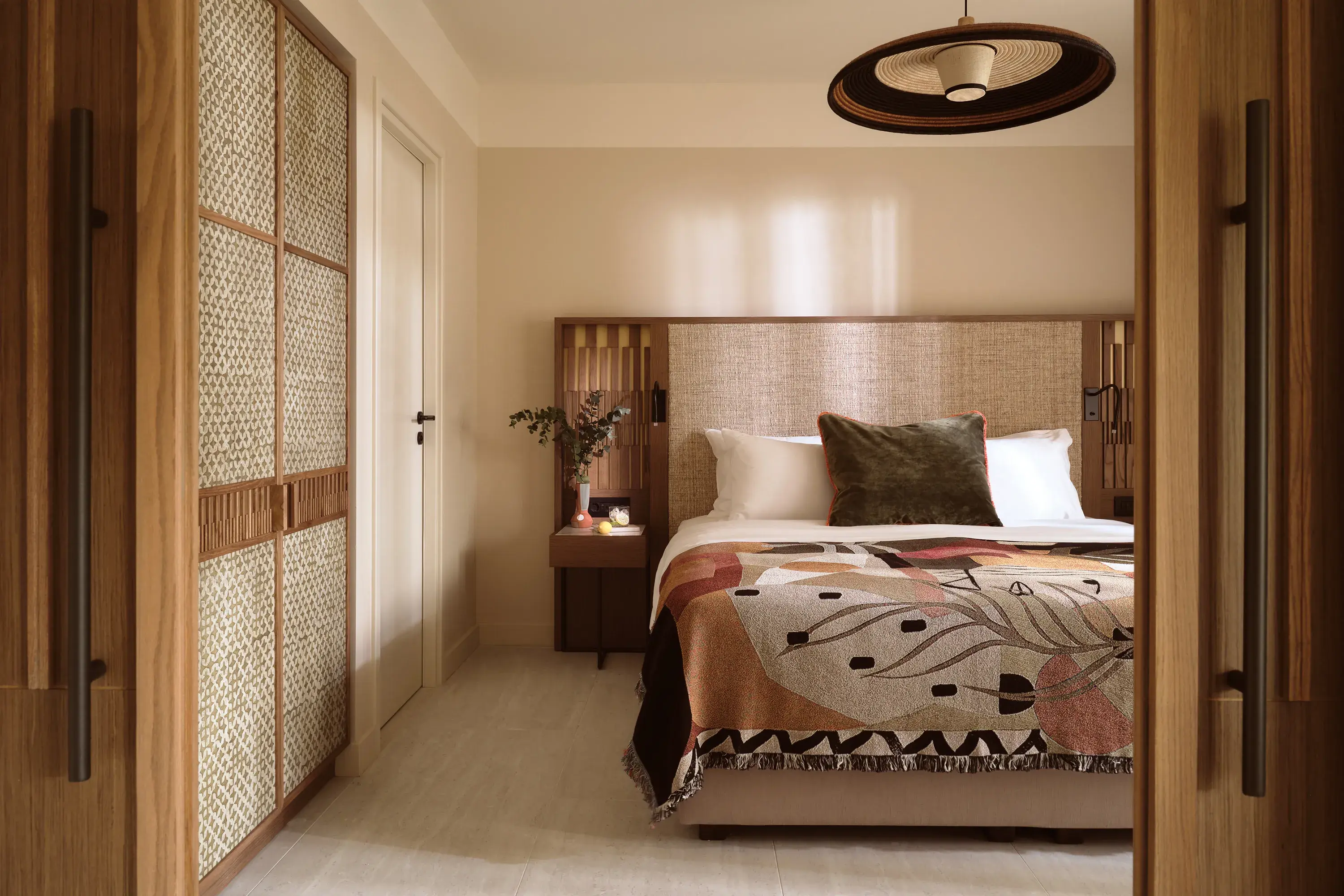 Elegant deluxe suite bedroom at Eagles Palace in Greece featuring natural wood accents, soft lighting and a stylish patterned throw.