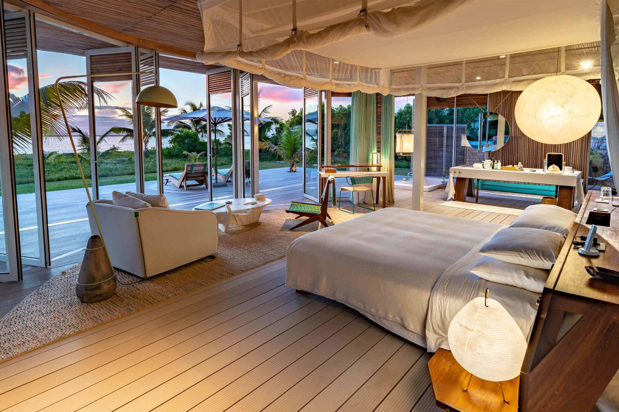 Bedroom of a private villa at Miavana Madagascar with lights on at twilight