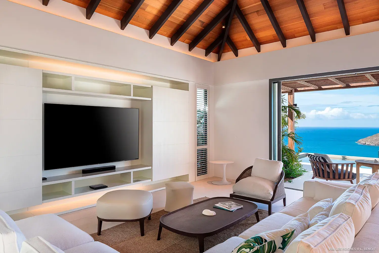 Bright, open‑plan living room at Les Roches Villa in St Barths featuring modern décor, vaulted wood ceiling and panoramic ocean views.