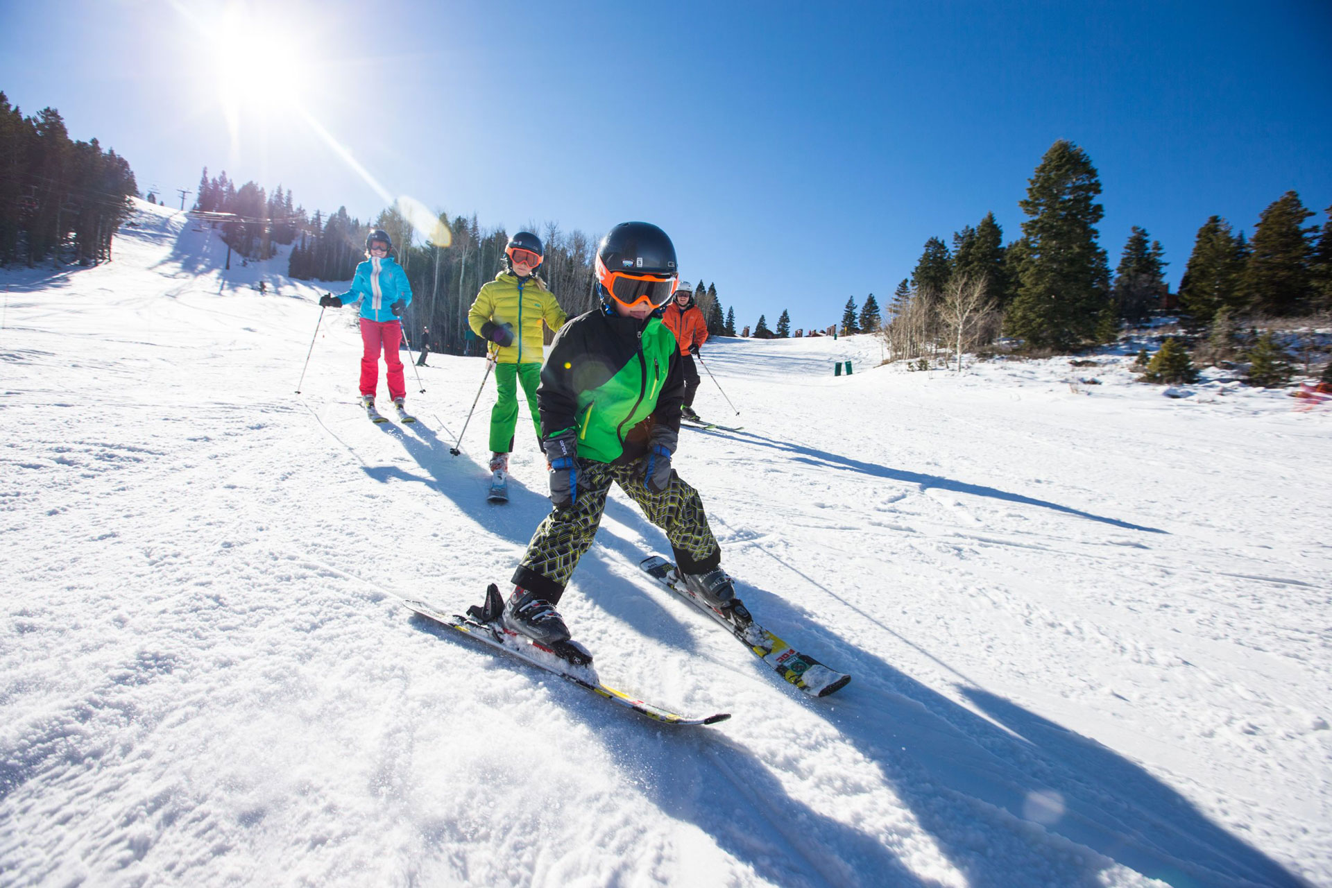 A child skiing towards the camera with a family following behind
