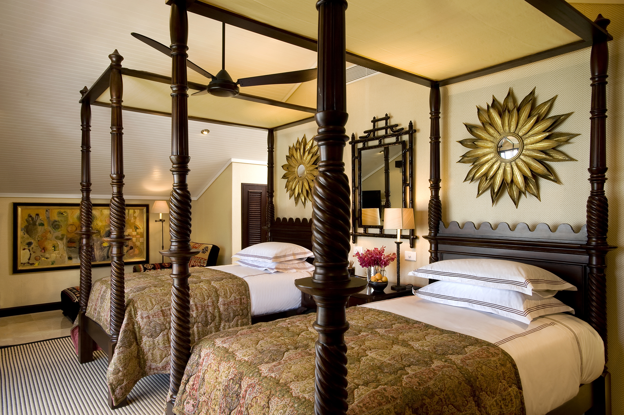 Twin four-poster beds with ornate mirrors above in a cosy bedroom
