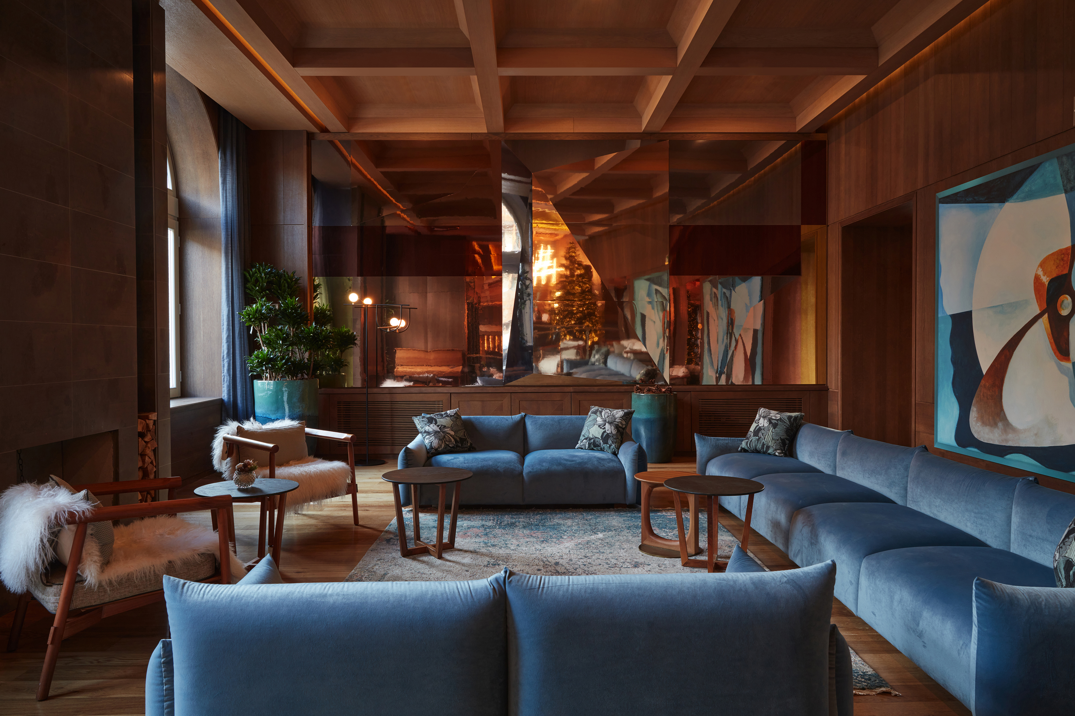 The cosy lobby of Grand Hotel Savoia decorated with blue sofas and geometric artwork beneath a coffered ceiling