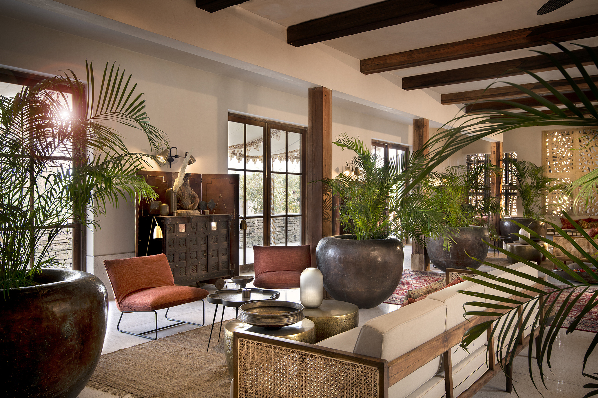 Lounge area at Aramness featuring large metal vases filled with palm leaves, comfy furniture and beamed ceilings