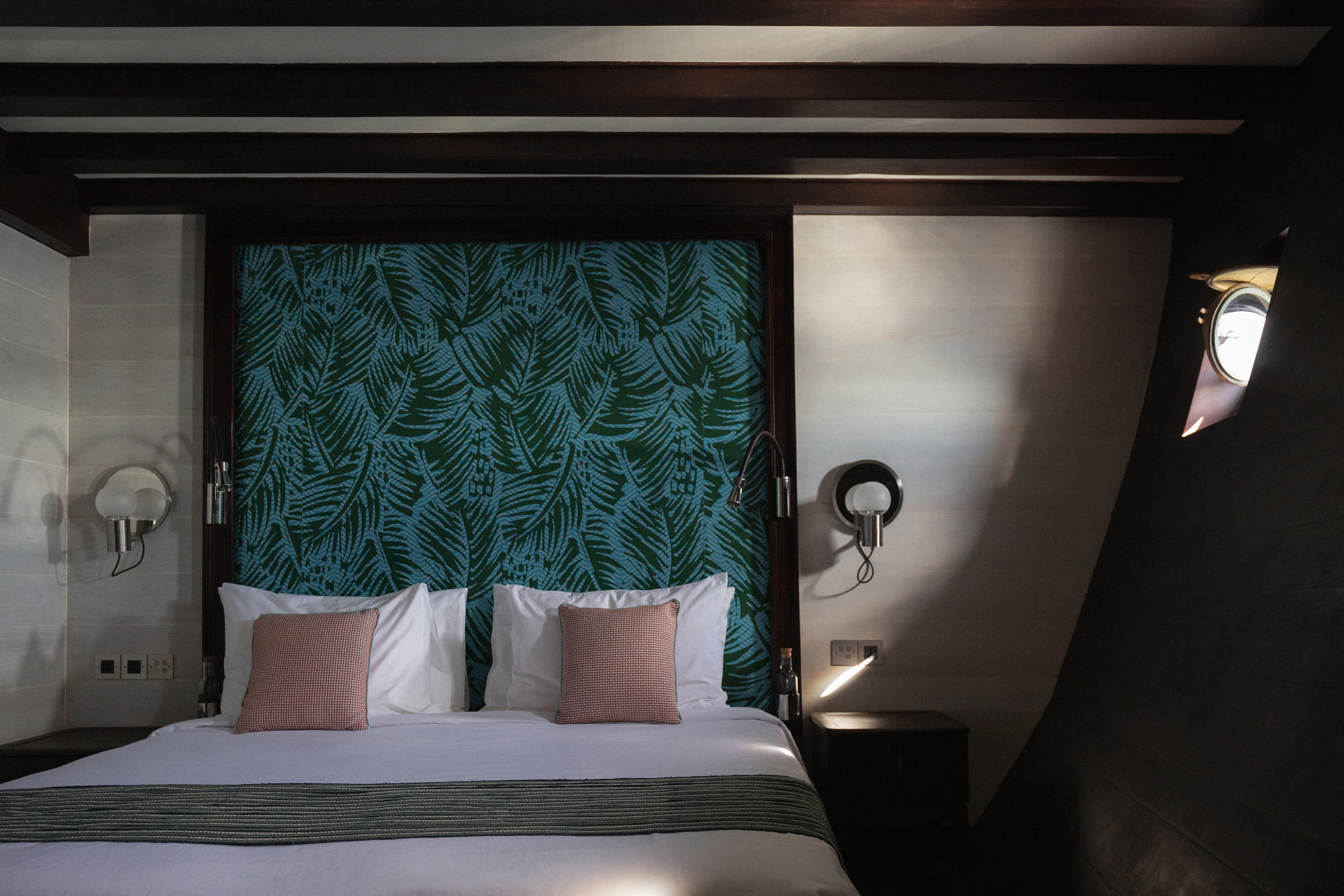 Stateroom of Vela featuring a comfy bed with green wallpaper and beams