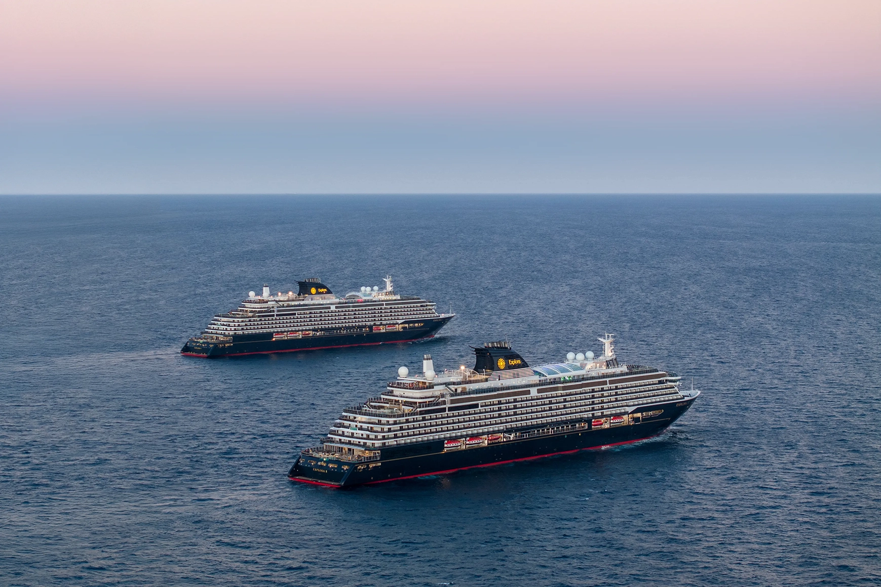 Explora I and II cruise ships sailing on the ocean near Miami under a pink sky
