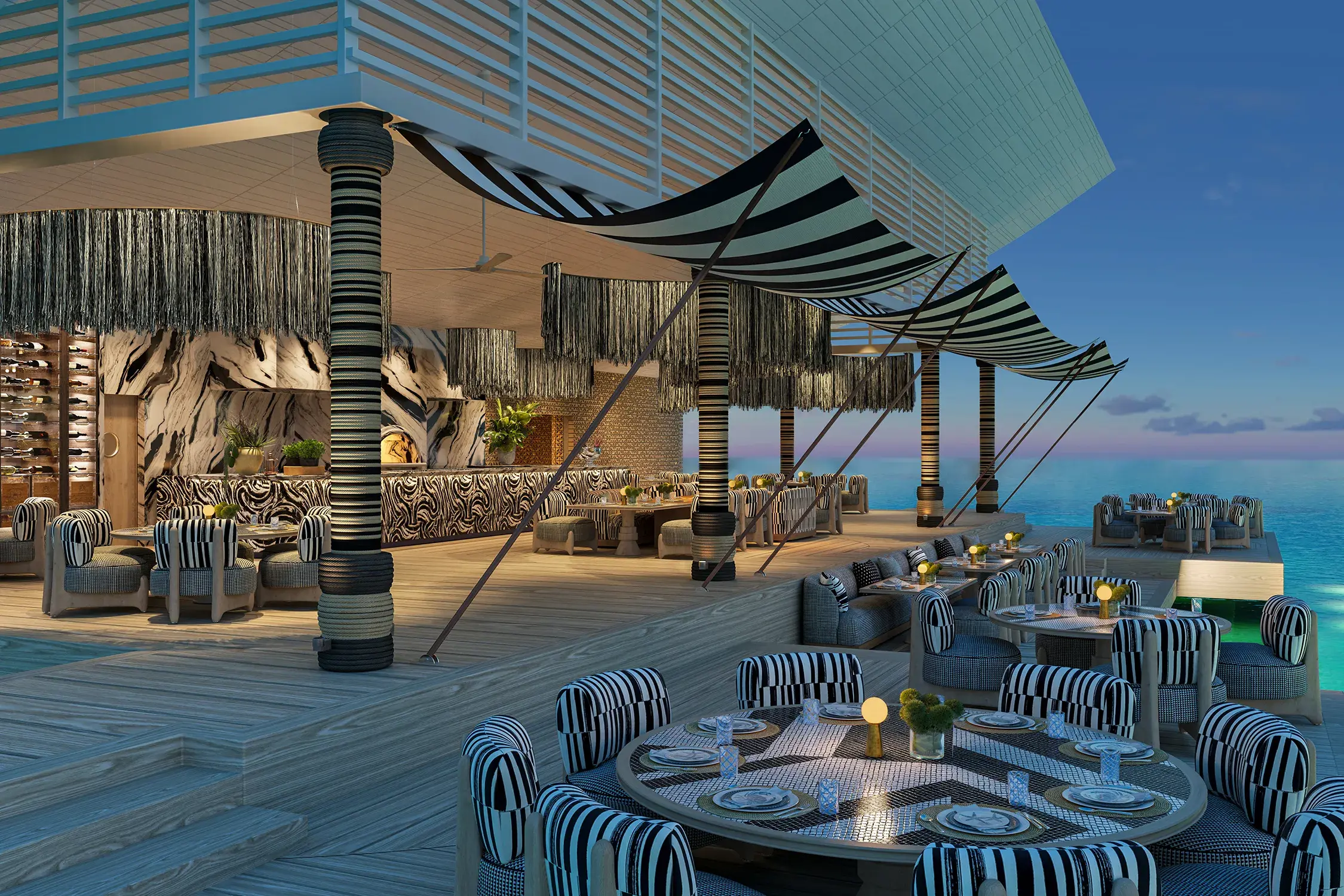 Oceanfront restaurant at .Here Resort in the Maldives with chic striped décor and sunset dining views.