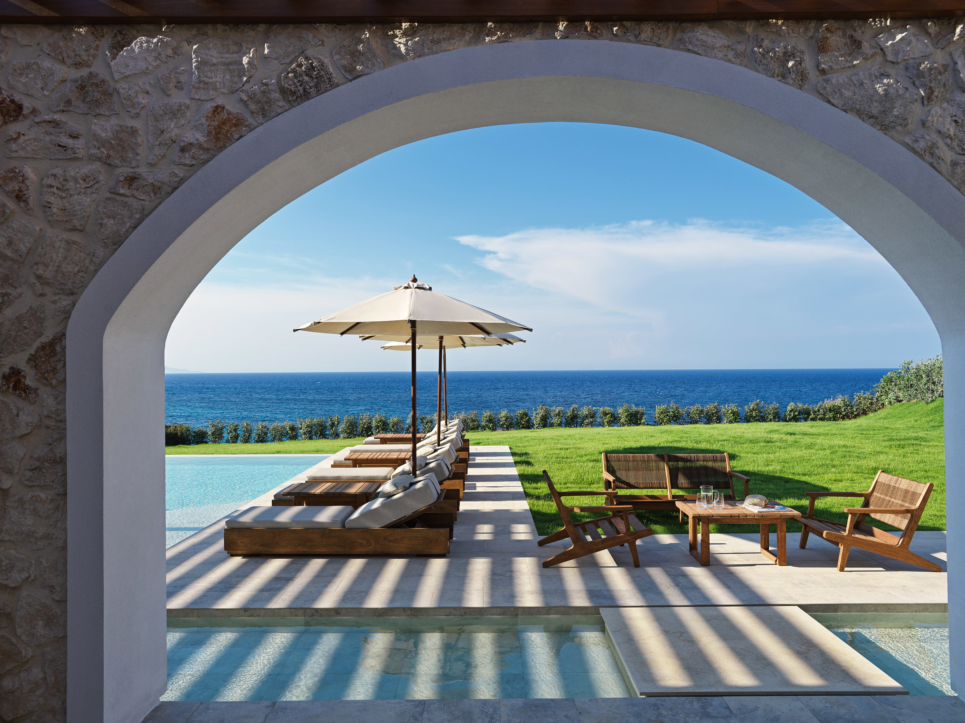 Pool loungers through an archway at Lesante Cape