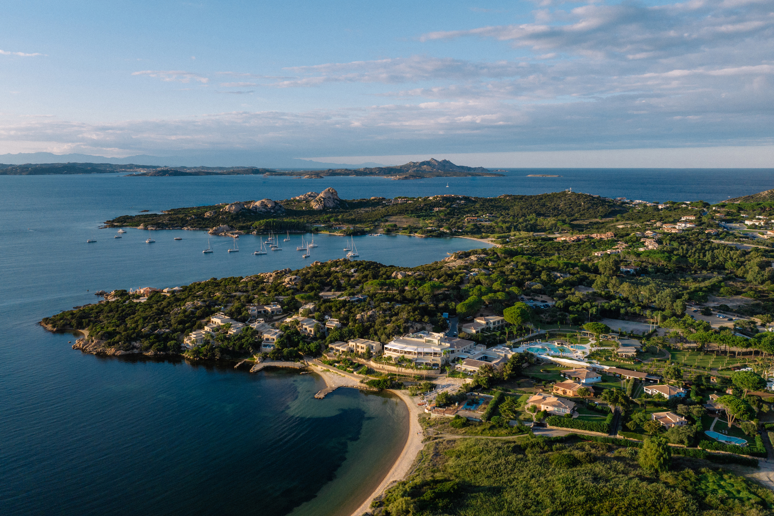 A view from the sky of 7Pines Resort Sardinia and its surrounding landscape of greenery and ocean