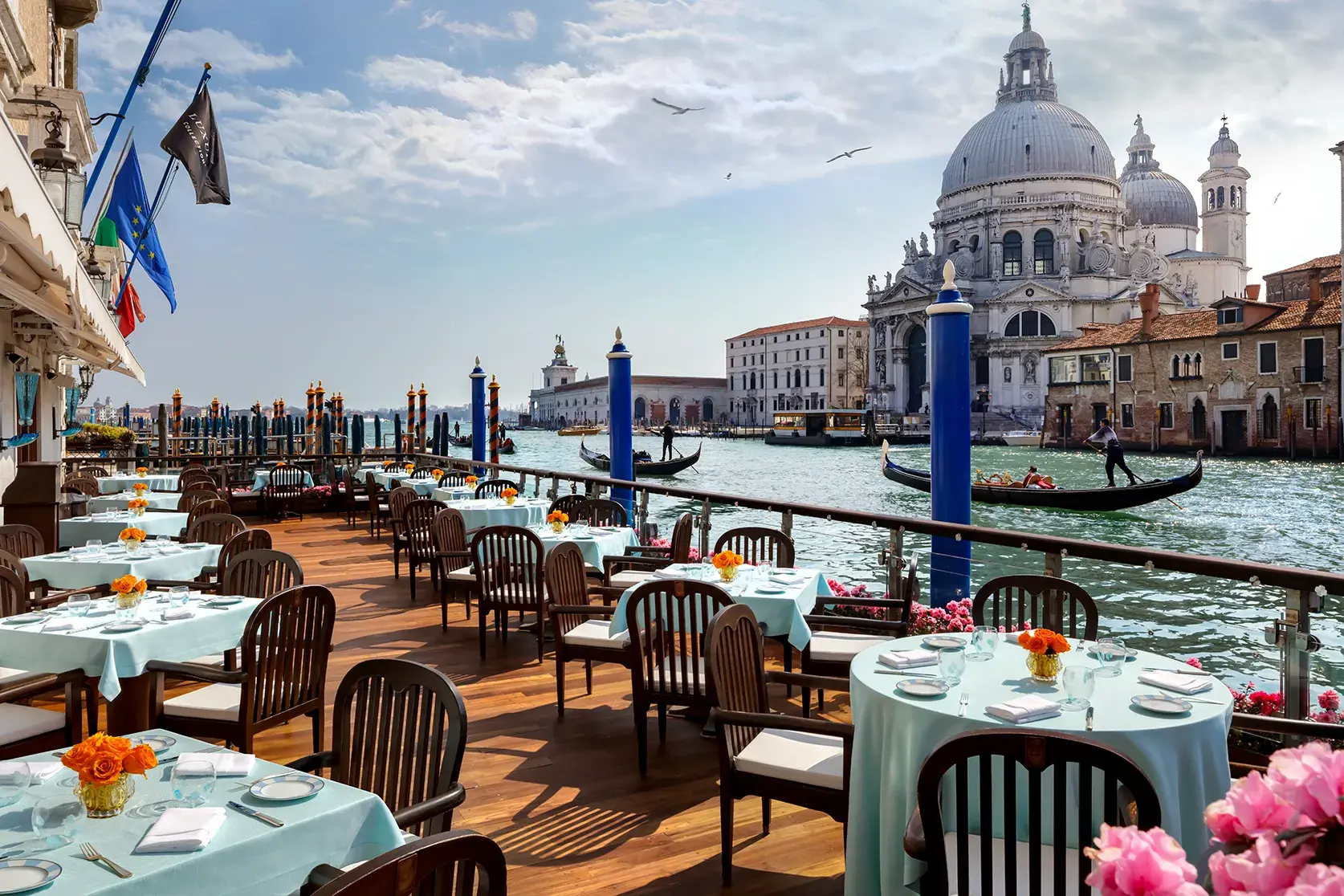 Outdoor terrace dining at The Gritti Palace in Venice overlooking the Grand Canal with views of Santa Maria della Salute and gondolas.