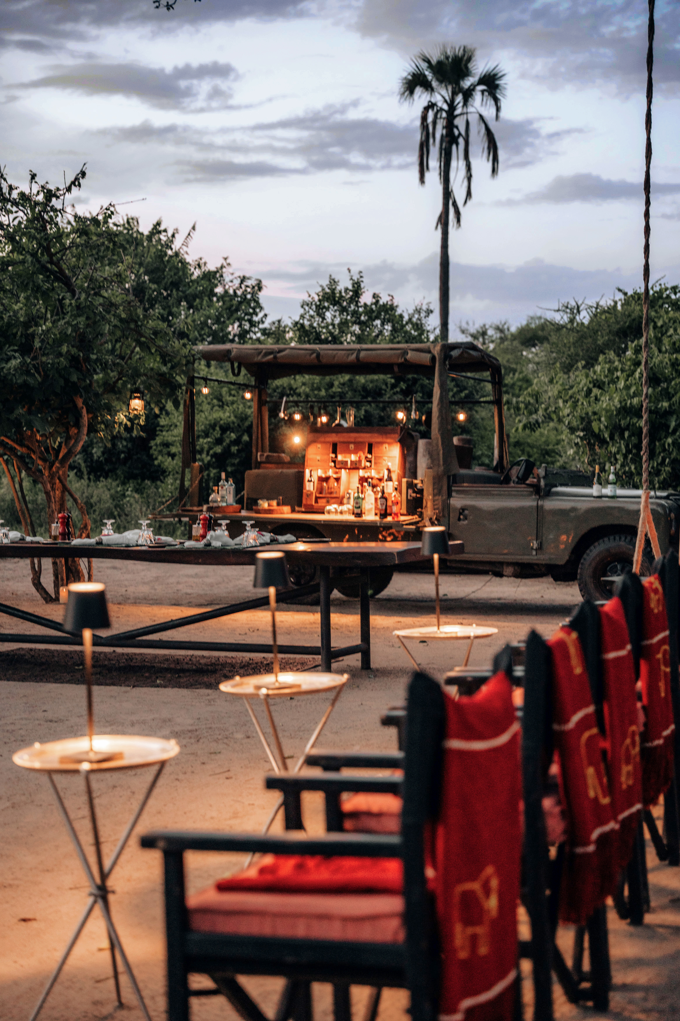 Table and chairs set up for drinks with a jeep bar in the background at sunset