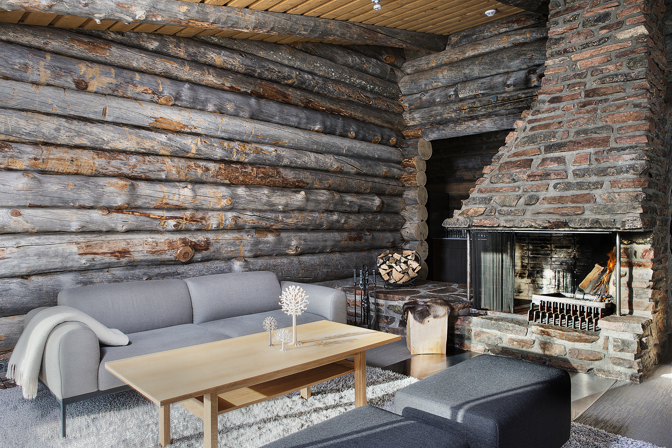 A chalet lounge with a fireplace and wooden log walls