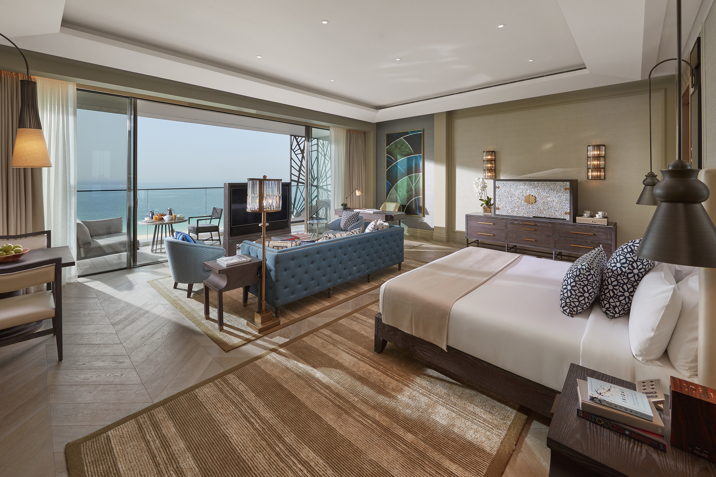 A modern yet opulent suite at Mandarin Oriental Jumeira, Dubai featuring a plush bed, blue sofa and large sliding doors