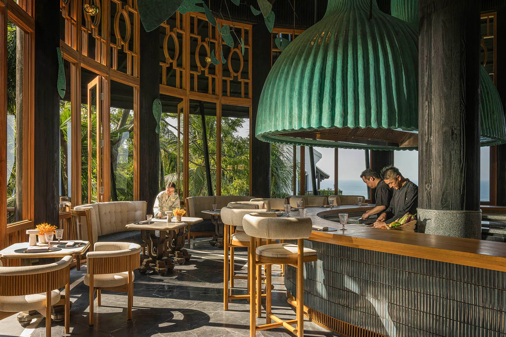 Asia, Vietnam, InterContinental Danang, Tingara Japanese restaurant, two men preparing food behind the bar and a woman laying tables 