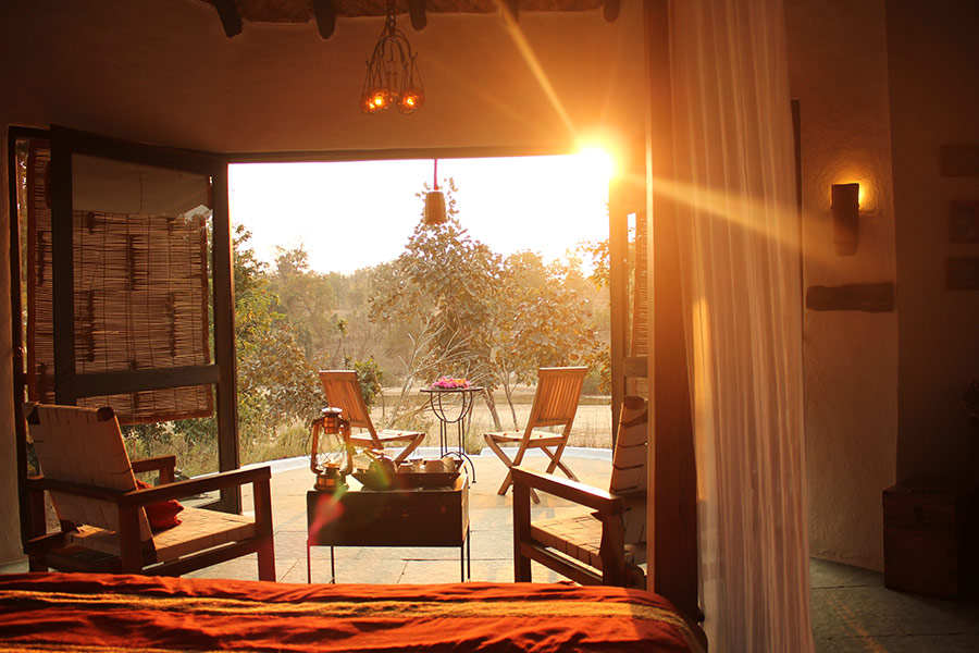 Asia, India, Flame of the forest,  sunlight shining into a bedroom through open double doors that lead to chairs on a terrace 