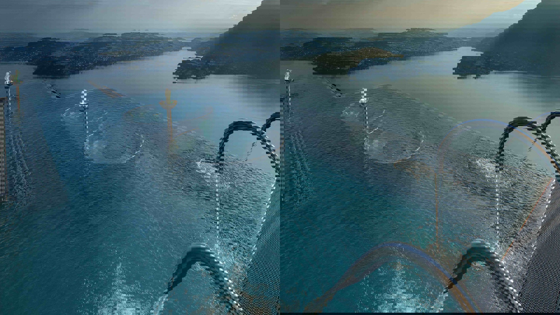 Burgenstock Hotel's infinity pool with a unique circular design overlooking Lake Lucerne and mountainous at dusk, creating a tranquil and luxurious setting.