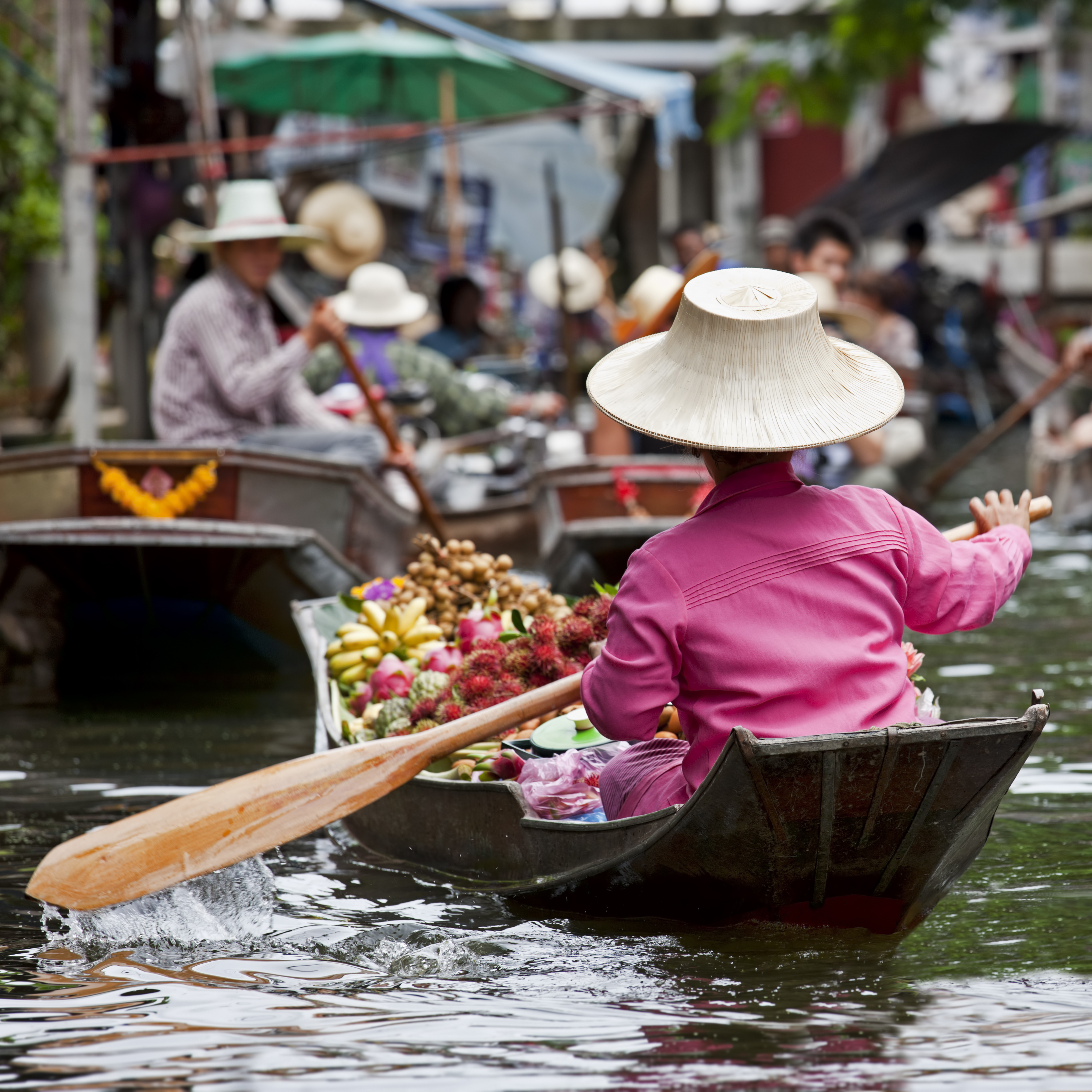 A person rowing a wooden boat filled with food