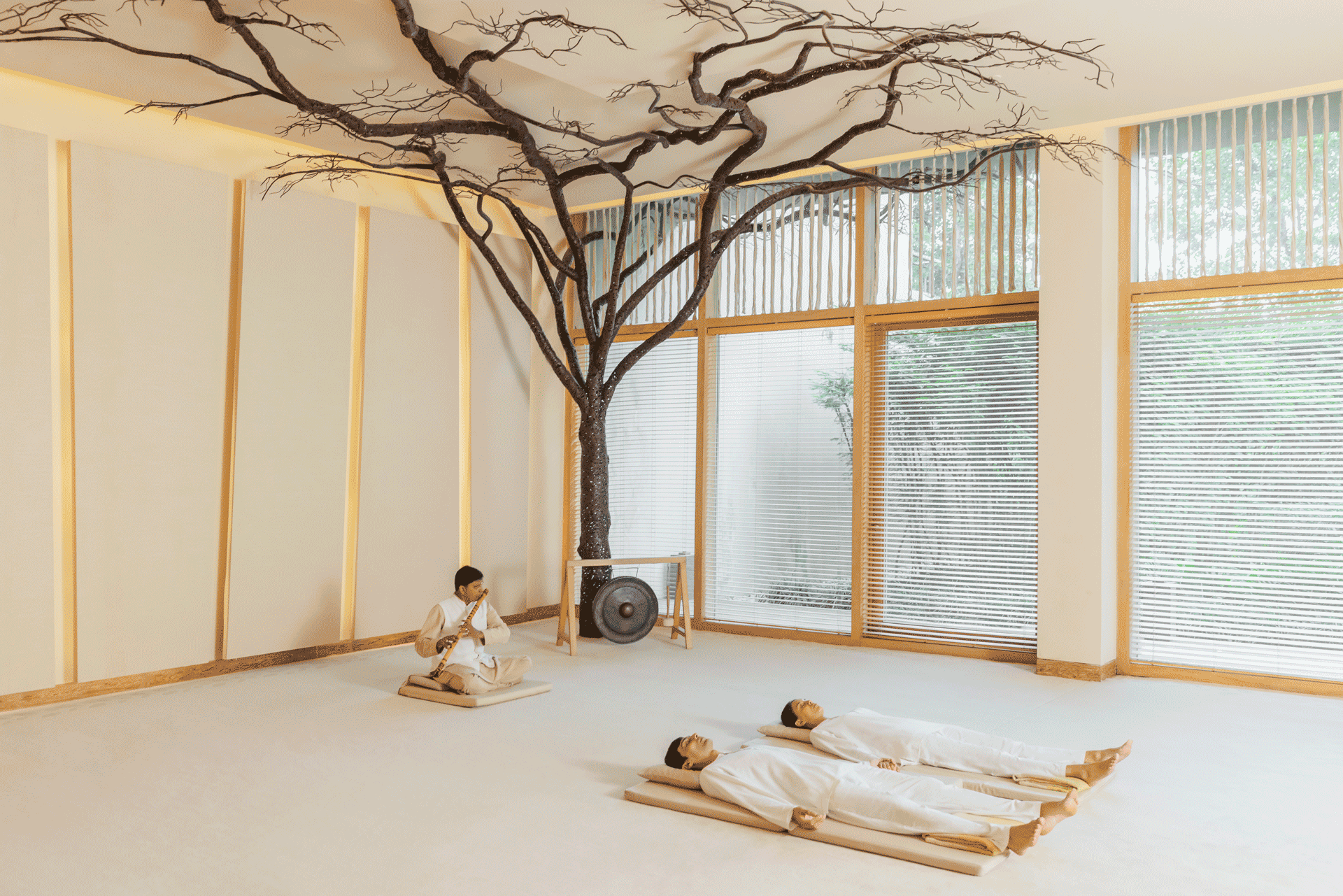 Sound therapy session at Royal Mansour Tamuda Bay with guests lying beneath a sculptural tree installation as live music is played in a serene wellness space.