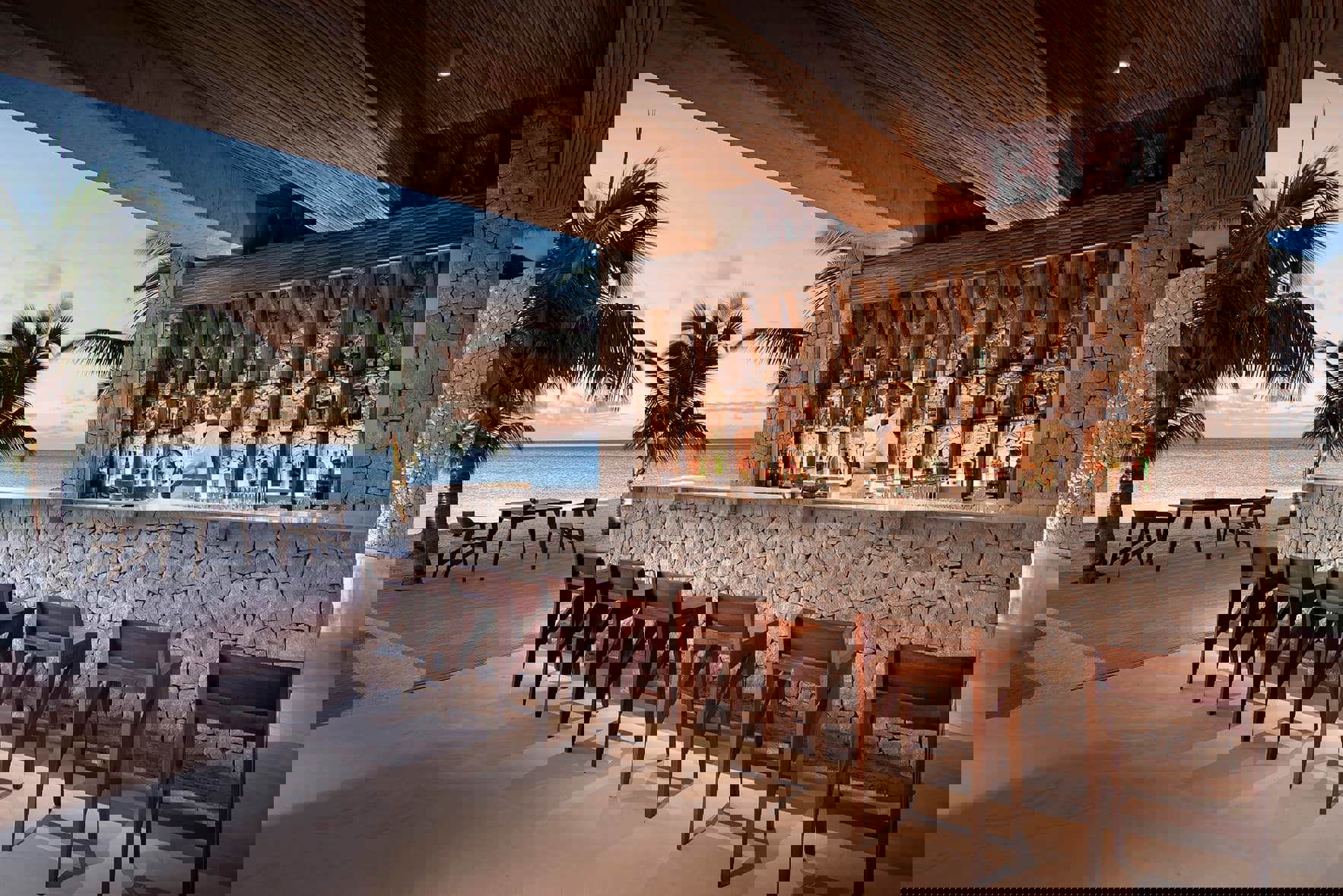 Bartender smiling behind bar lined with chairs 