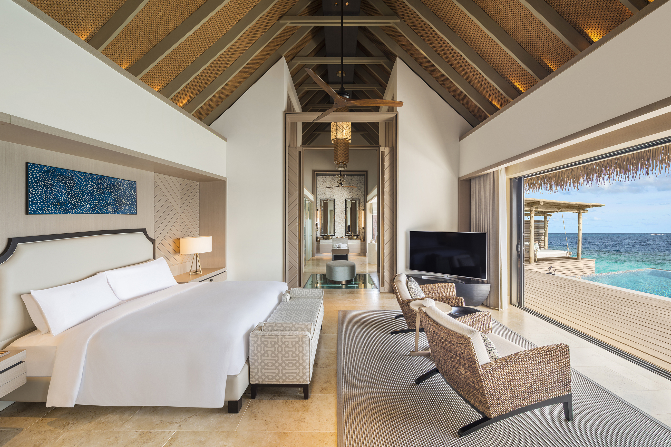 Bedroom of King Grand Overwater Villa with a neutral colour scheme and large doorway to outdoor terrace