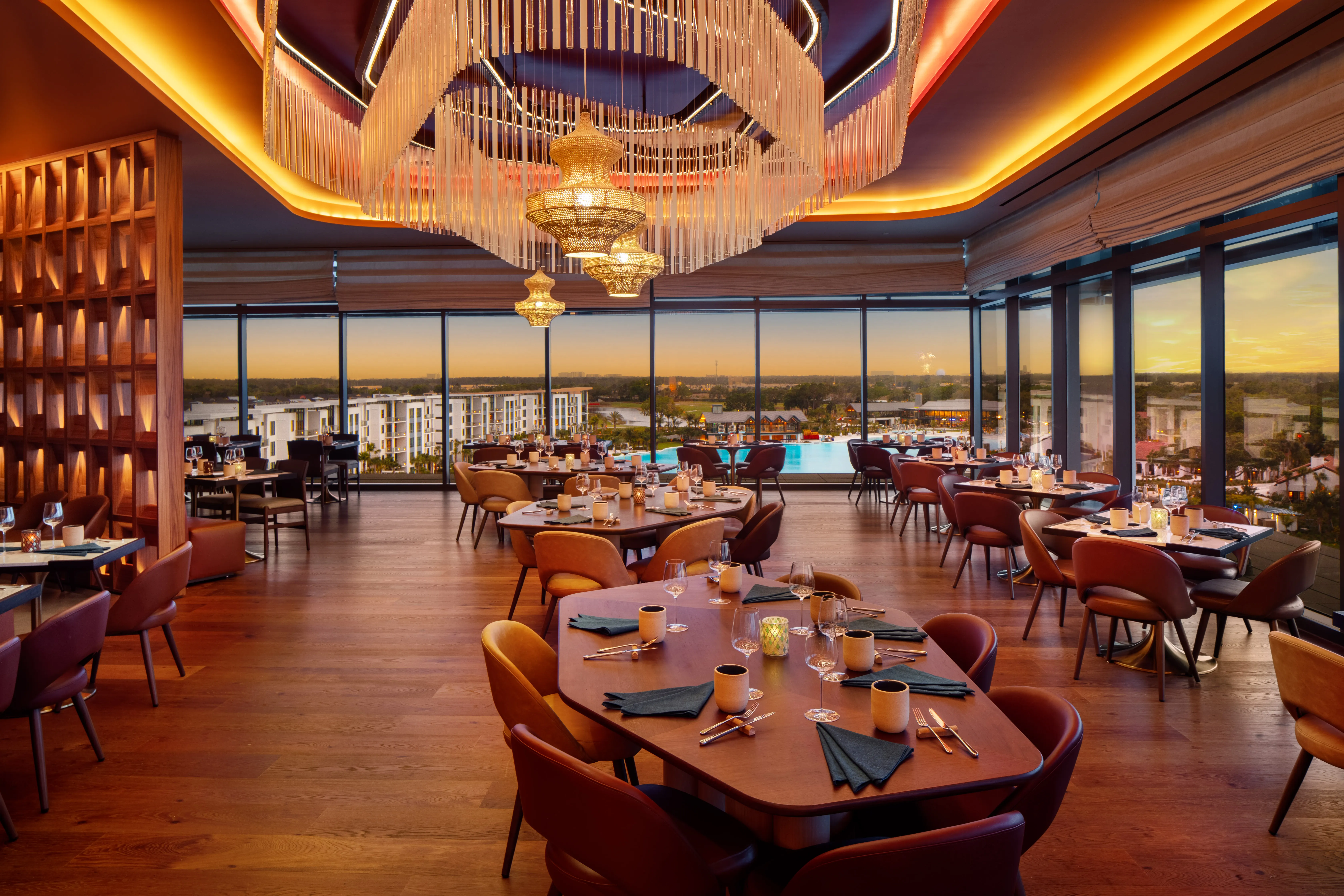 Upscale rooftop dining room at Conrad Orlando in Florida featuring elegant chandeliers, modern décor, and panoramic sunset views.