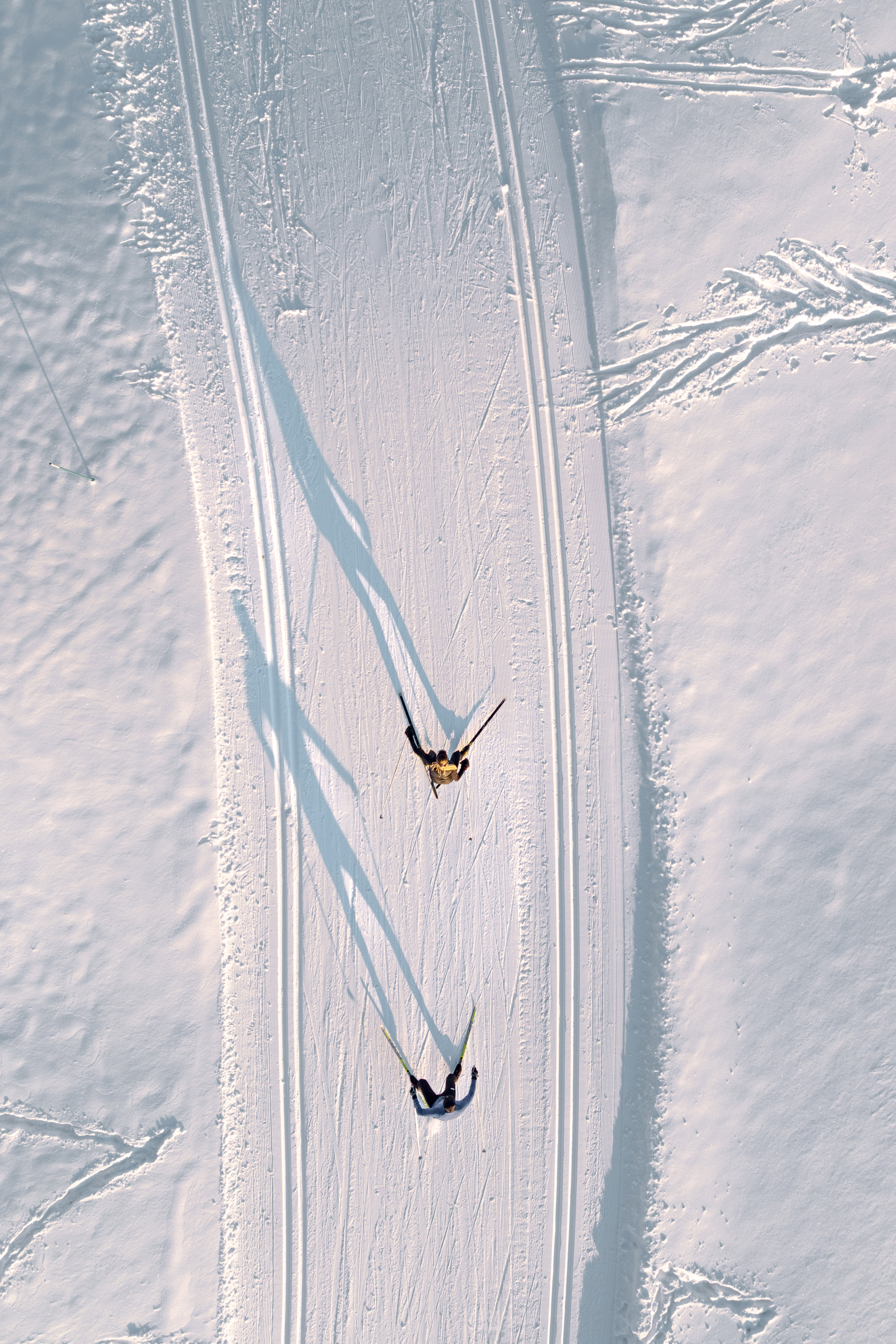 A birds eye view of two skiers on a trail