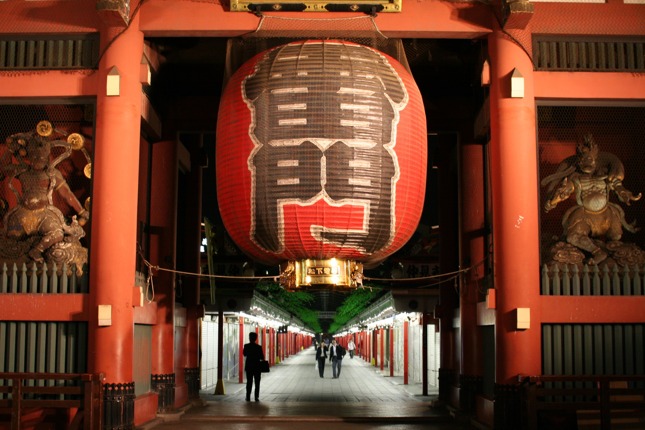 The red enterance of Asakusa temple in Tokyo featuring a large red lantern and people walking a pathway beneath