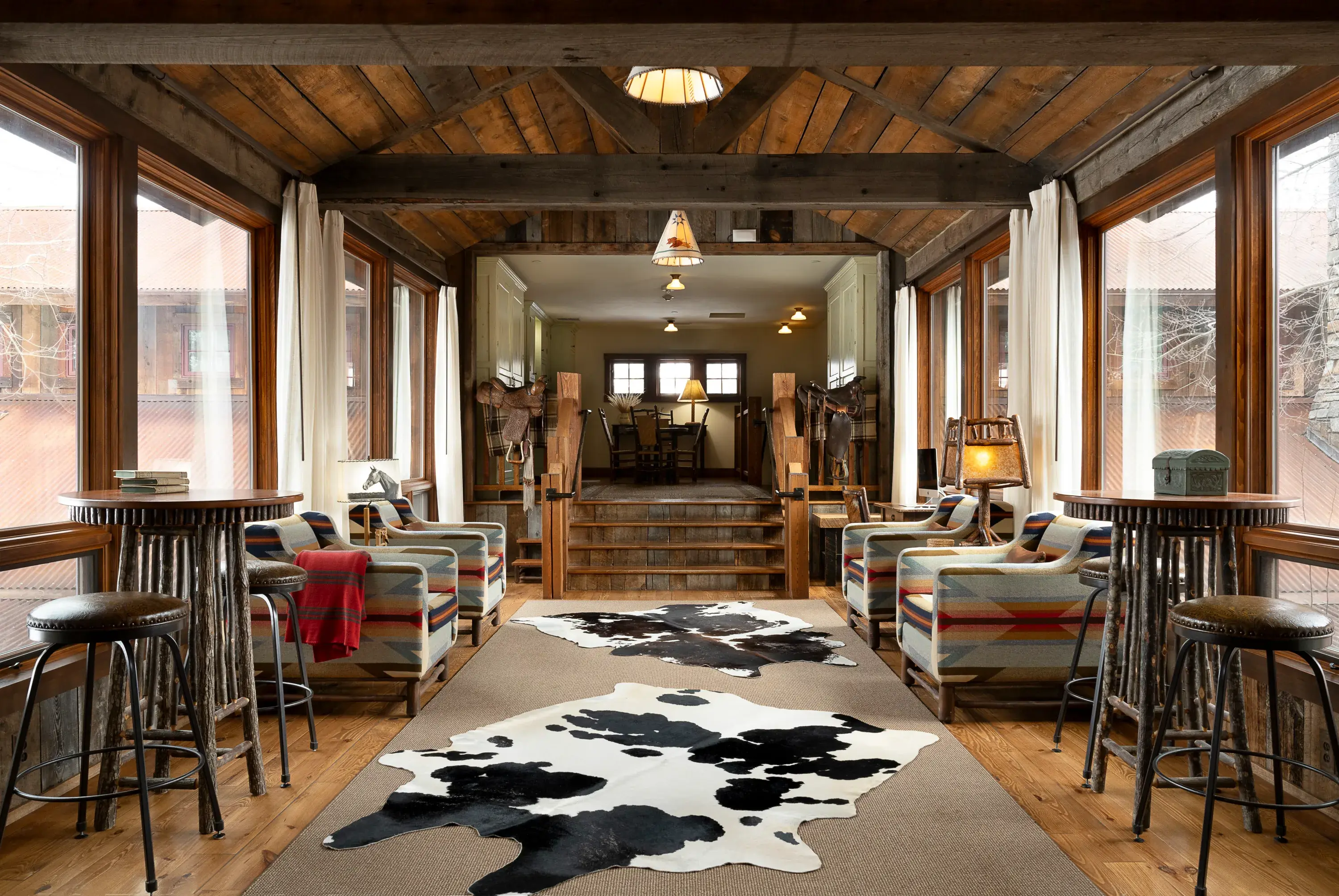 Indoor bridge area linking two parts of the Granite Lodge at The Ranch at Rock Creek in Montana featuring a cow print rug, geometric patterned furniture and a small set of stairs