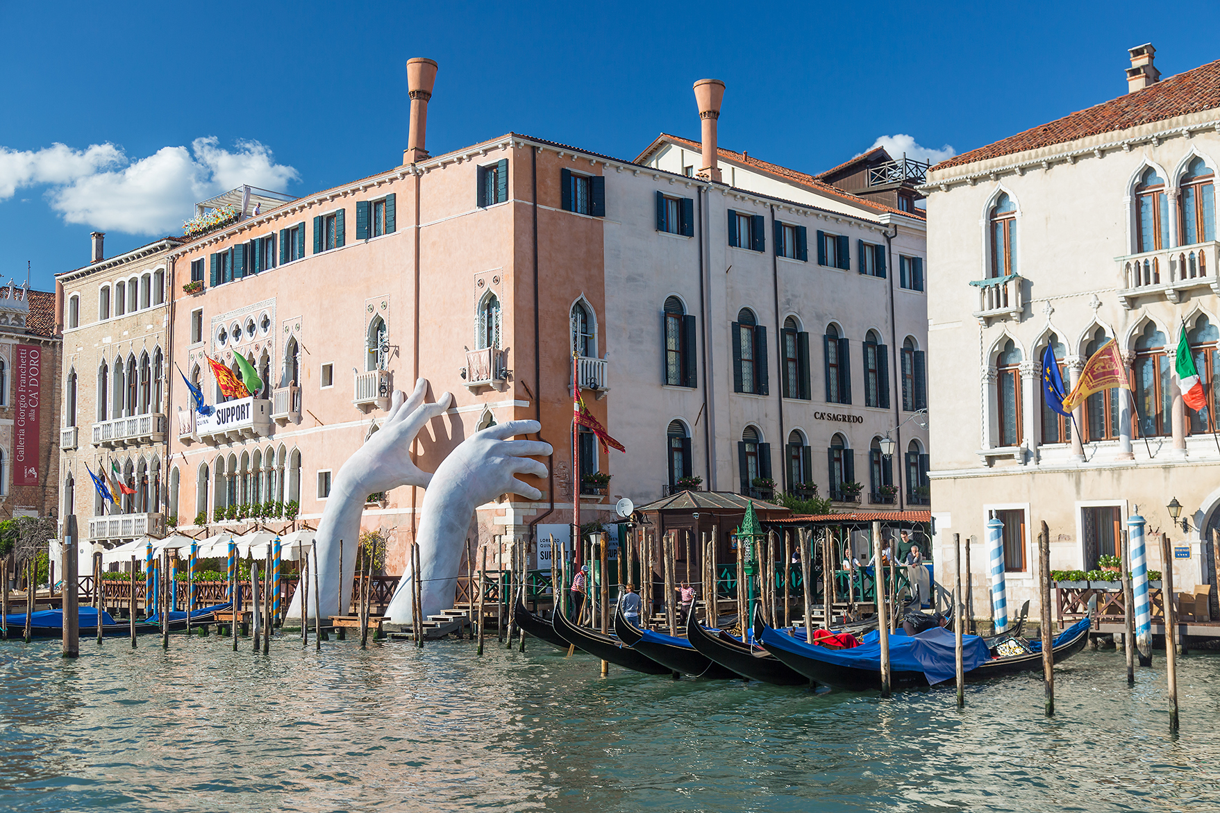 A sculpture of two hands reaching out of the water in Venice 