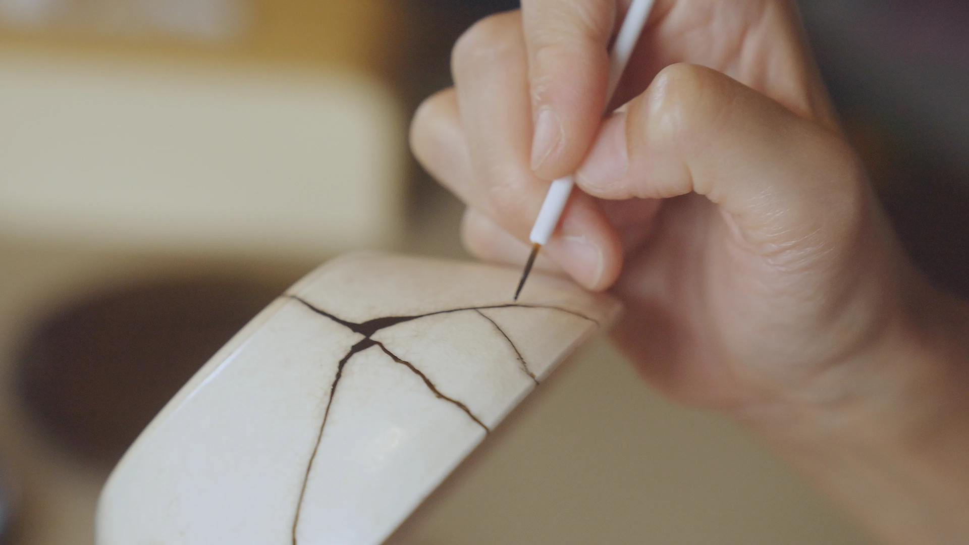 Woman repairing broekn pottery with gold with the Japanese Kintsugi technique 